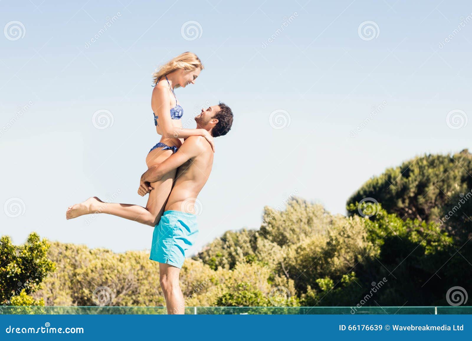 Девушка носит парня на руках. Мужчина несет девушку на пляже. Парень несёт девушку на вытянутых руках. Парень несёт девушку на руках на пляже. Человека несут на вытянутых руках.