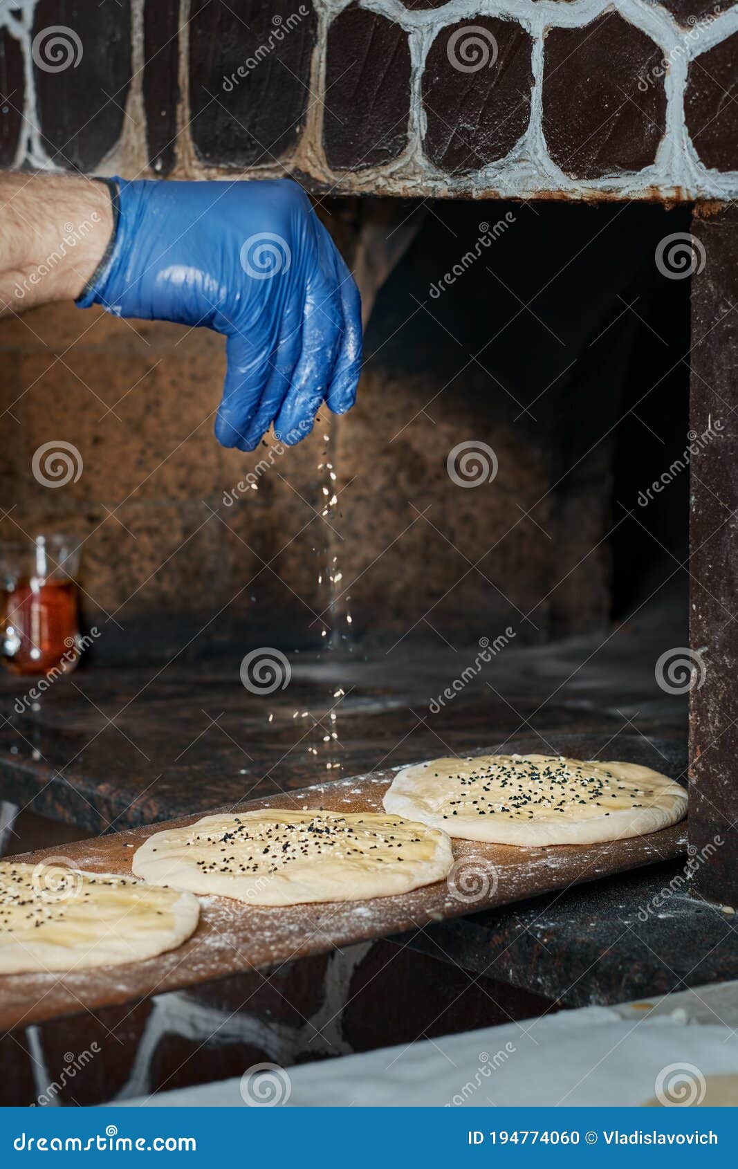 Перед печь в духовке шеф-повар брызгами булочки с семена кунжута. Булочки  для того, чтобы сделать традиционное Doner Tombik Duner Стоковое Фото -  изображение насчитывающей кухня, тимон: 194774060