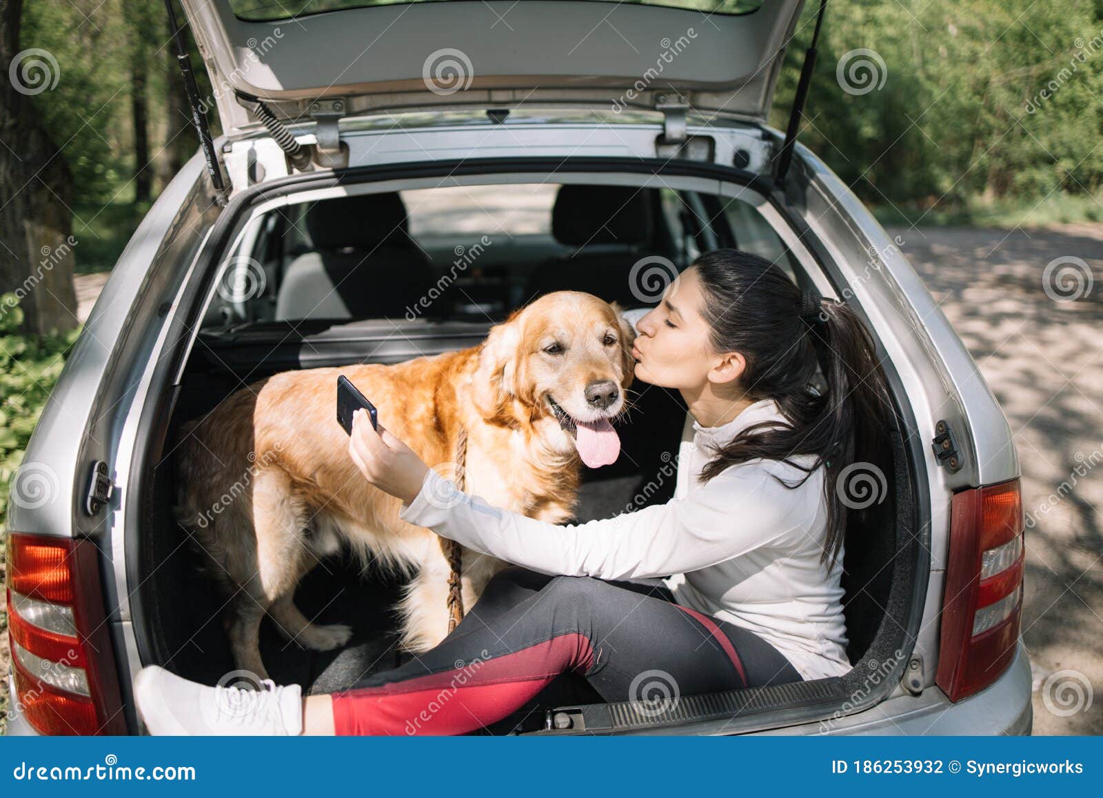 Пес, сидящий в багажнике, в то время как девушка целует его Стоковое Фото -  изображение насчитывающей золотисто, счастливо: 186253932