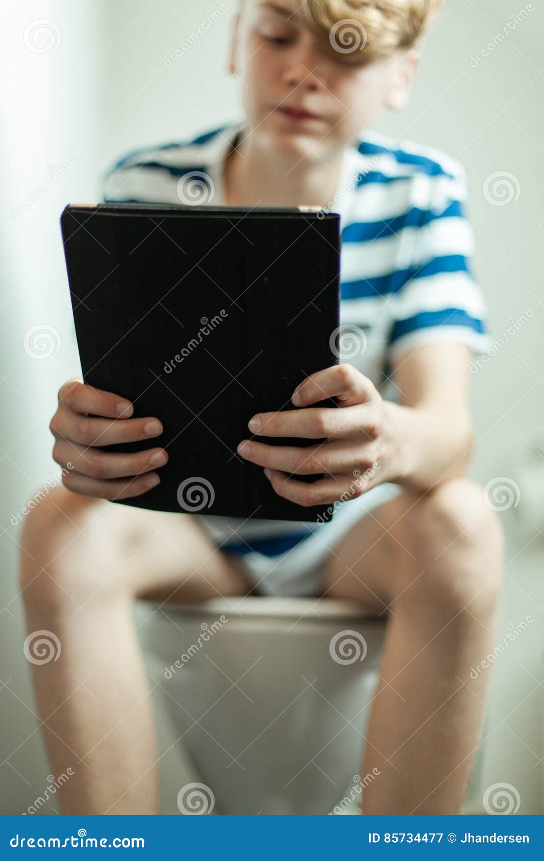 Thoughtful boy sitting on the toilet. фотография Stock Adobe Stock
