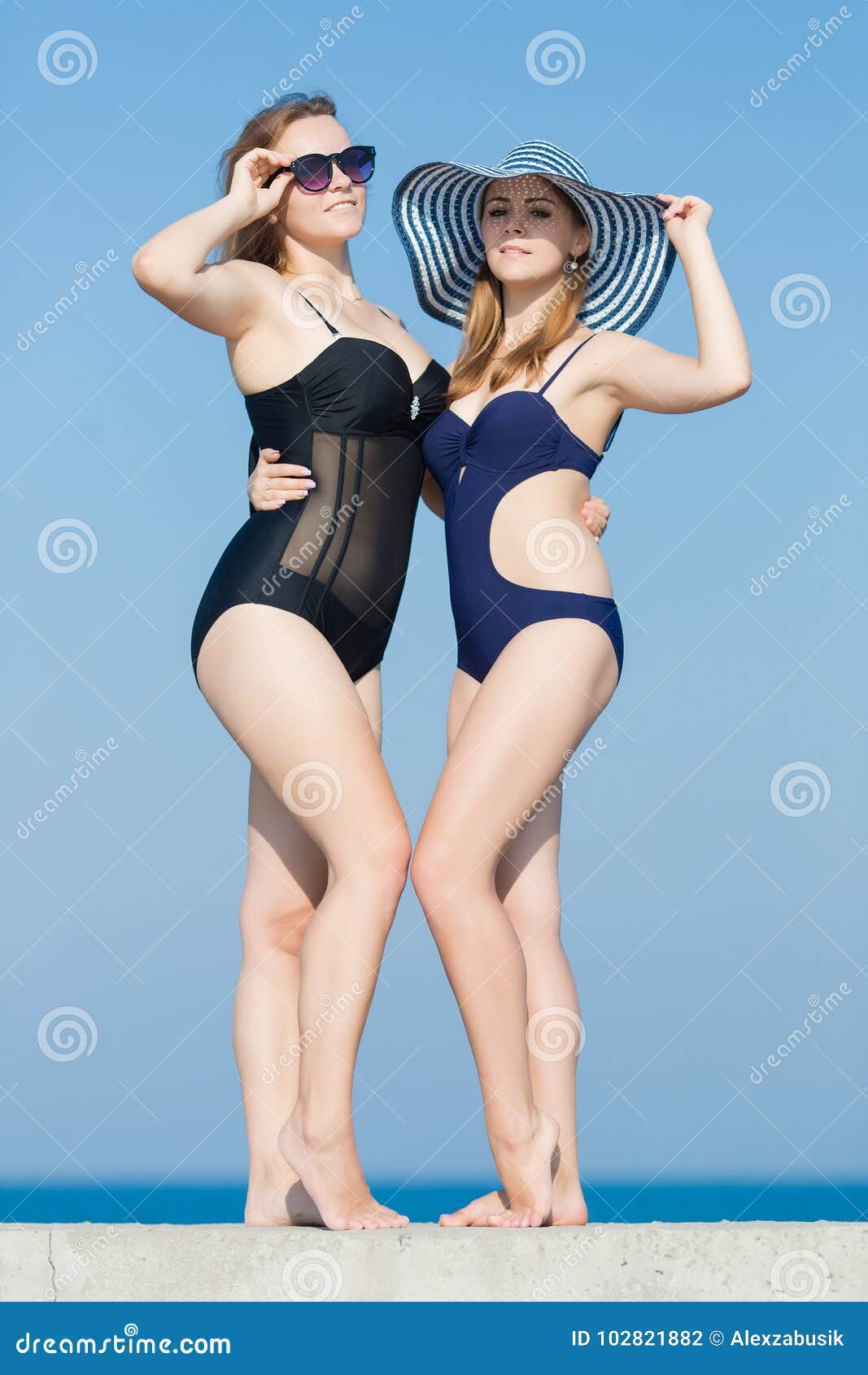 2 привлекательных молодой женщины в купальниках против неба Стоковое Фото -  изображение насчитывающей смотреть, оголенные: 102821882