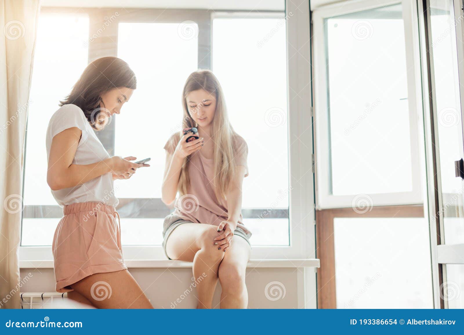 Приятные хорошие девочки, которые держат смартфоны Loooking на фотографии  Стоковое Фото - изображение насчитывающей вскользь, кресло: 193386654