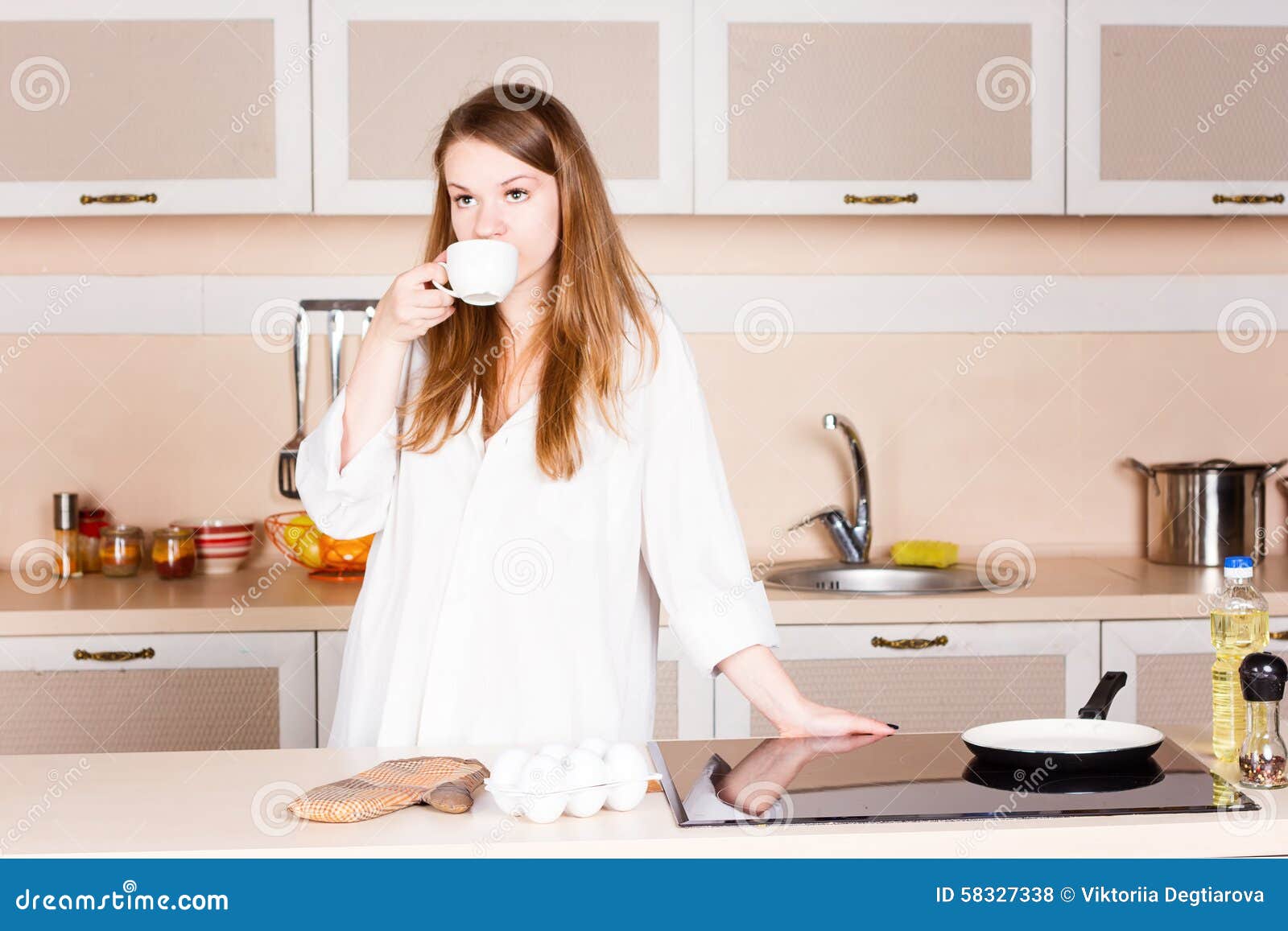 Попить на кухне. Девушка пьет кофе на кухне. Девушка пьет чай на кухне. Девушки пьют на кухне. Девочка пьёт чай на кухне.