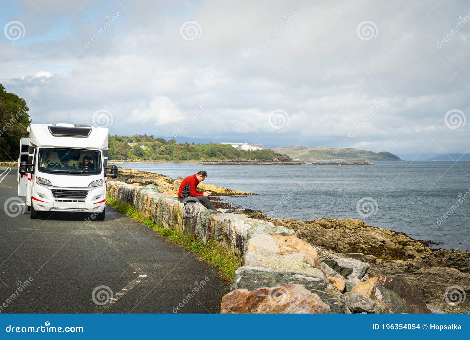 Семейный отдых летом в Motorhome. Мужской водитель принимая перерыв и глядя  на мобильный телефон на автостоянки морем. Стоковое Фото - изображение  насчитывающей кемпинг, семья: 196354054