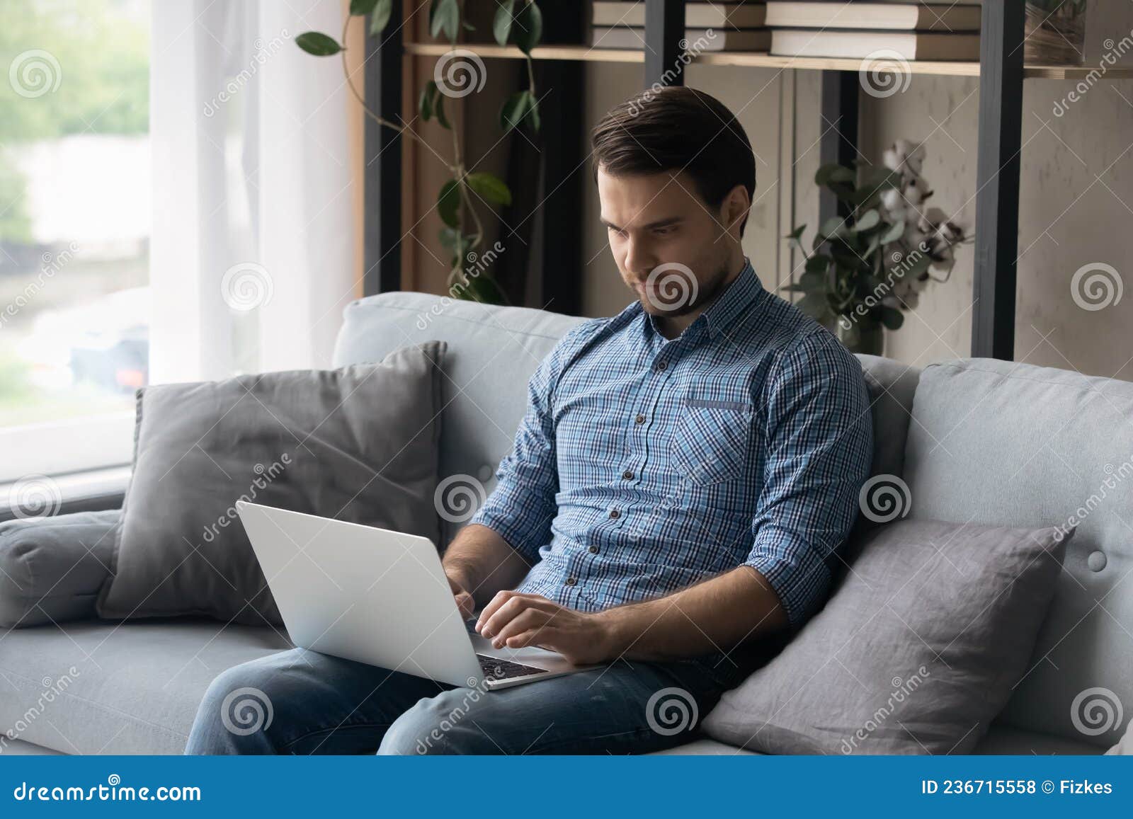 серьезный человек сидит дома на диване с ноутбуком Стоковое Фото -изображение насчитывающей дело, просматривают: 236715558