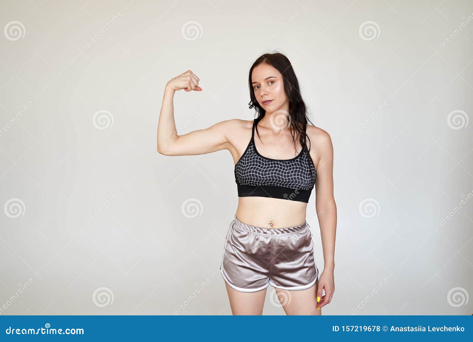 Сильная спортивная девушка в спортивной топе и трусиках демонстрирует мускулы оружия на белом фоне с копировальным пространством Стоковое Фото - изображение насчитывающей женщина, сторона: 157219678