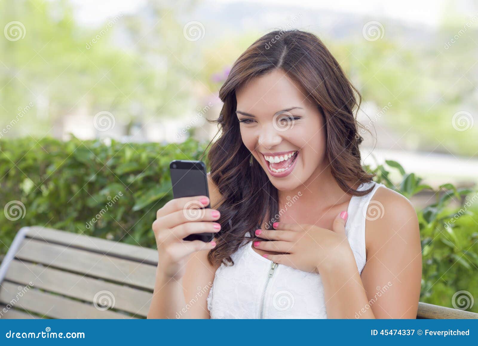 Усмехаясь Молодая Взрослая Женщина Отправляя СМС На Сотовом.