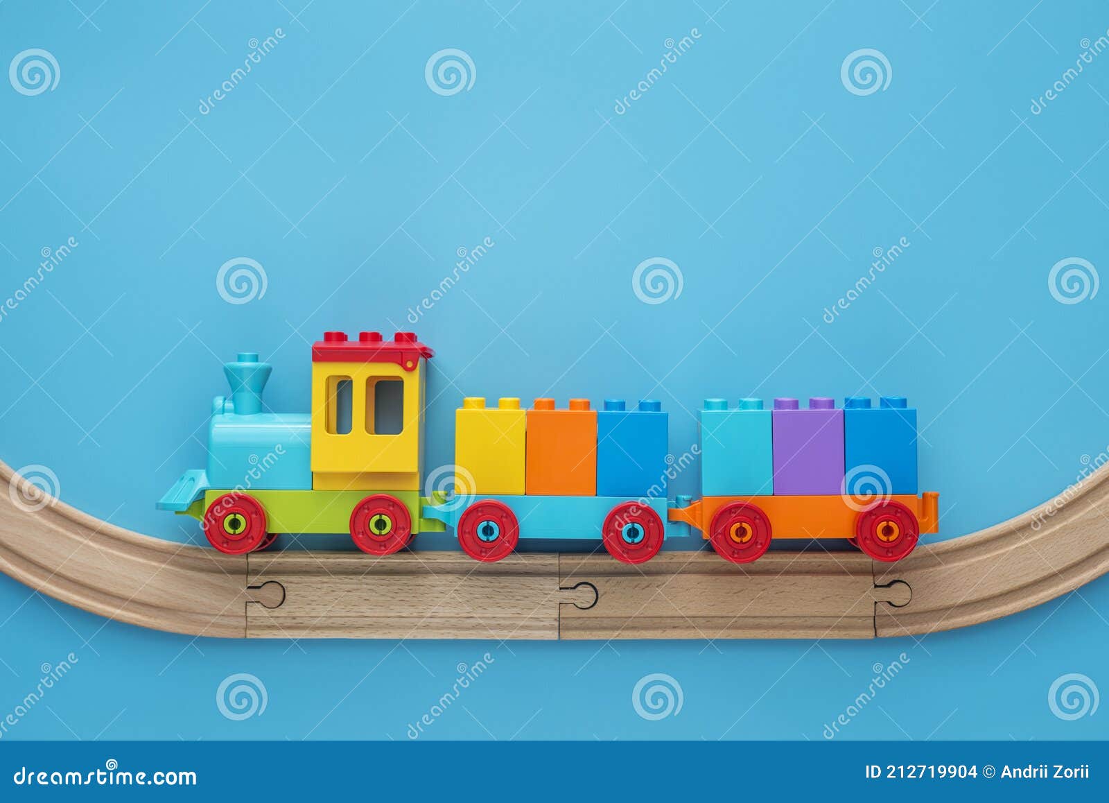Фон игрушек с пространством для копирования. Дети забавляются поезд с 2  вагонов на железной дороге на синем фоне дерева с простран Стоковое Фото -  изображение насчитывающей цветасто, экипаж: 212719904