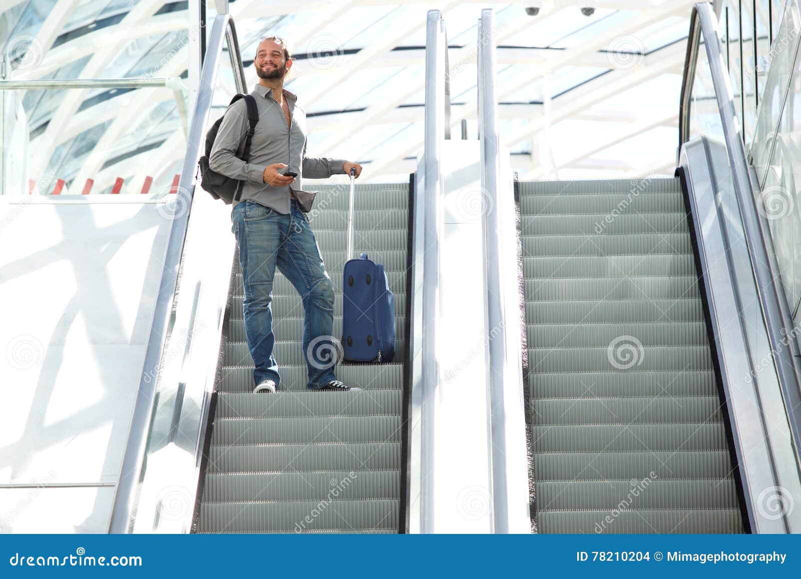 Эскалатор метрополитена поднимает неподвижно. Человек вверх на эскалаторе. Эскалатор со стоящим на нем человеком. Портрет мужчины на эскалаторе. Эскалатор и чемоданы.
