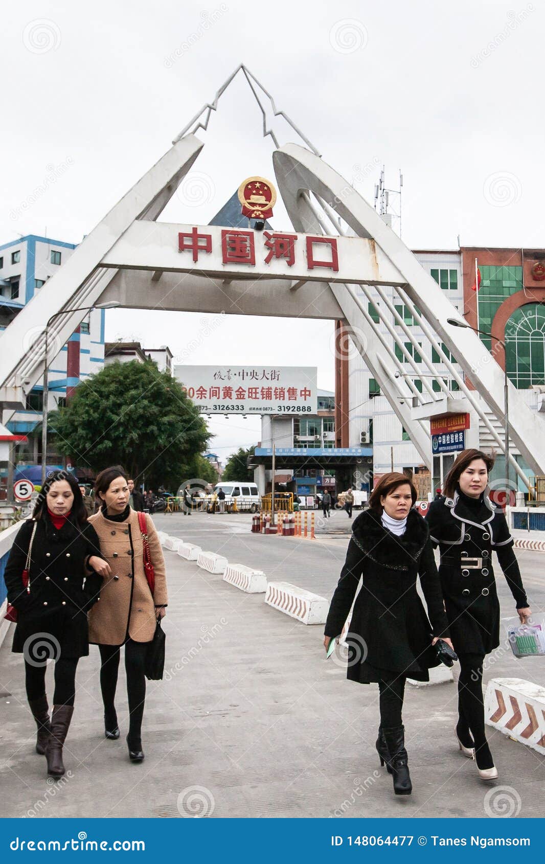 一个小组横渡在红河的桥梁的长的外套的亚裔妇女从河口 中国背景向老街市 图库摄影片 图片包括有一个小组横渡在红河的桥梁的长的外套的亚裔妇女从河口 中国背景向老街市 148064477