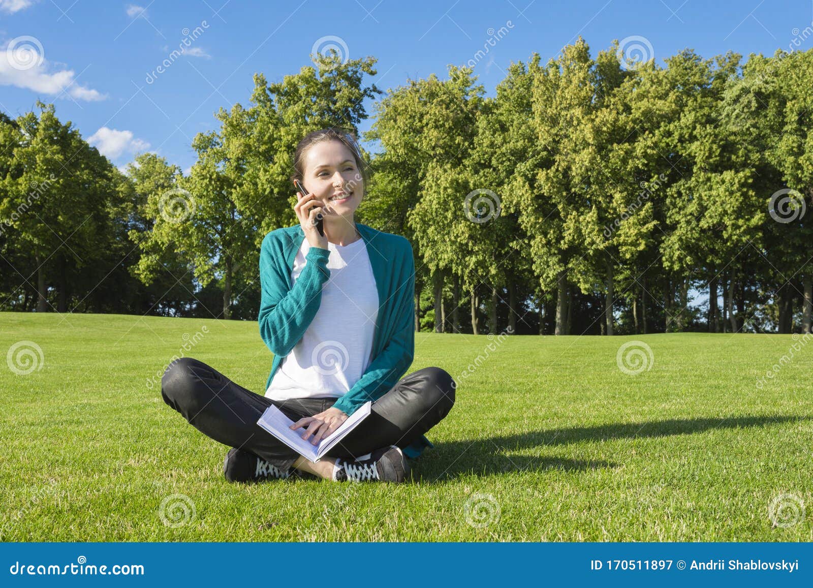 一个微笑的女孩正坐在草地上 手里拿着一本书 在阳光明媚的日子里库存图片 图片包括有生活方式 记事本