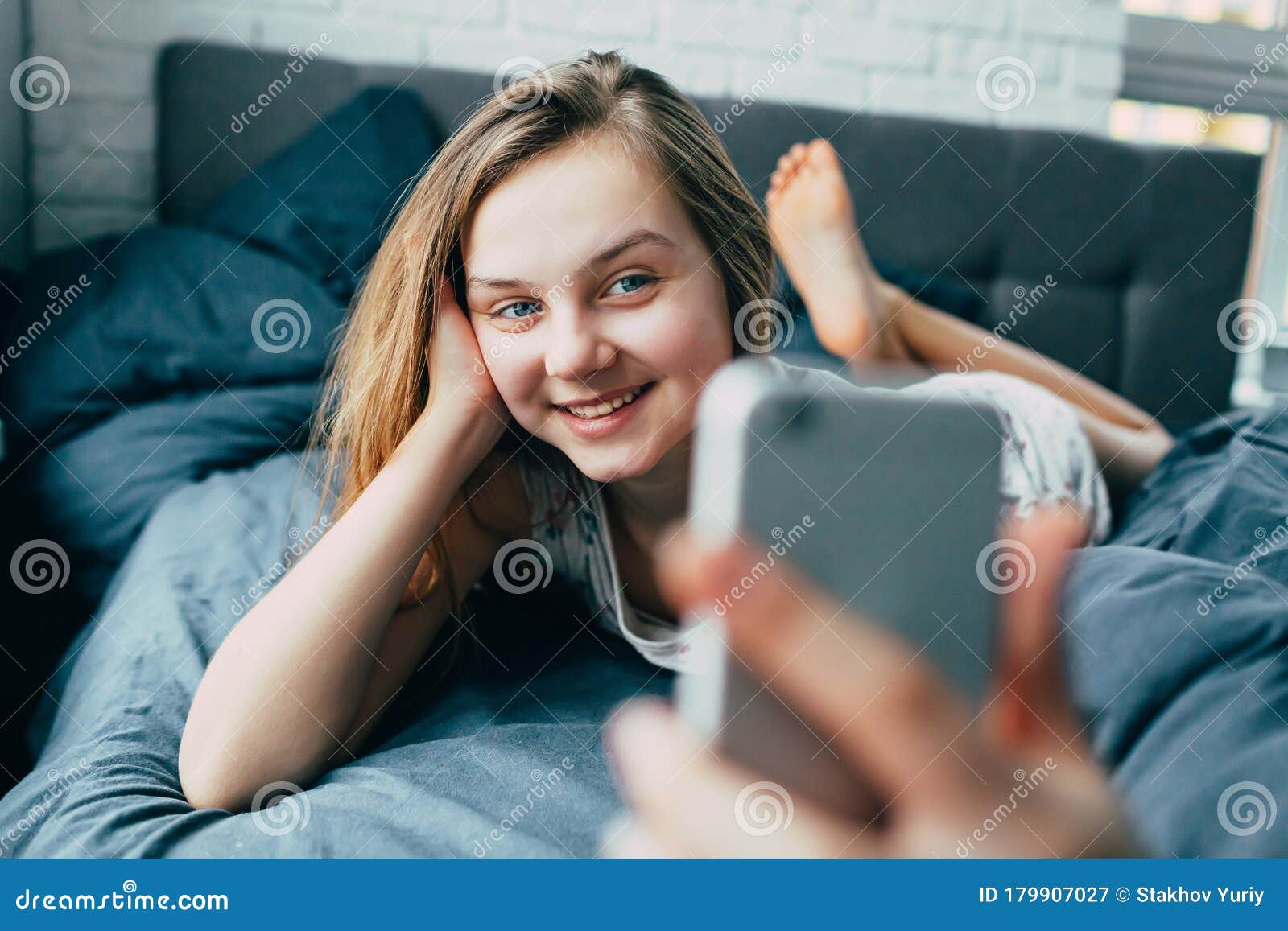 一个穿着睡衣的年轻白人少女躺在床上 手持电话在他面前 微笑着和朋友交流 库存图片 图片包括有谎言 藏品 一个穿着睡衣的年轻白人少女躺在床上 手持电话在他面前 微笑着和朋友交流 库存图片 图片包括有谎言 藏品