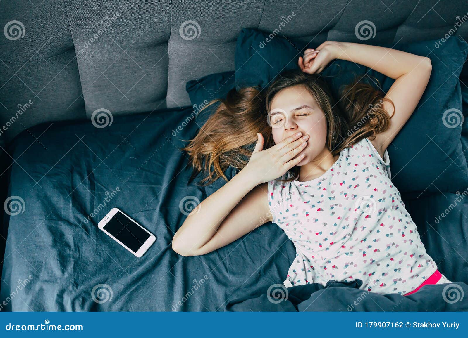 一个穿睡衣的白人少女刚醒 躺在电话旁的床上 用手捂住嘴 打哈欠库存照片 图片包括有消息 头发 一个穿睡衣的白人少女刚醒 躺在电话旁的床上 用手捂住嘴 打哈欠库存照片 图片包括有消息 头发