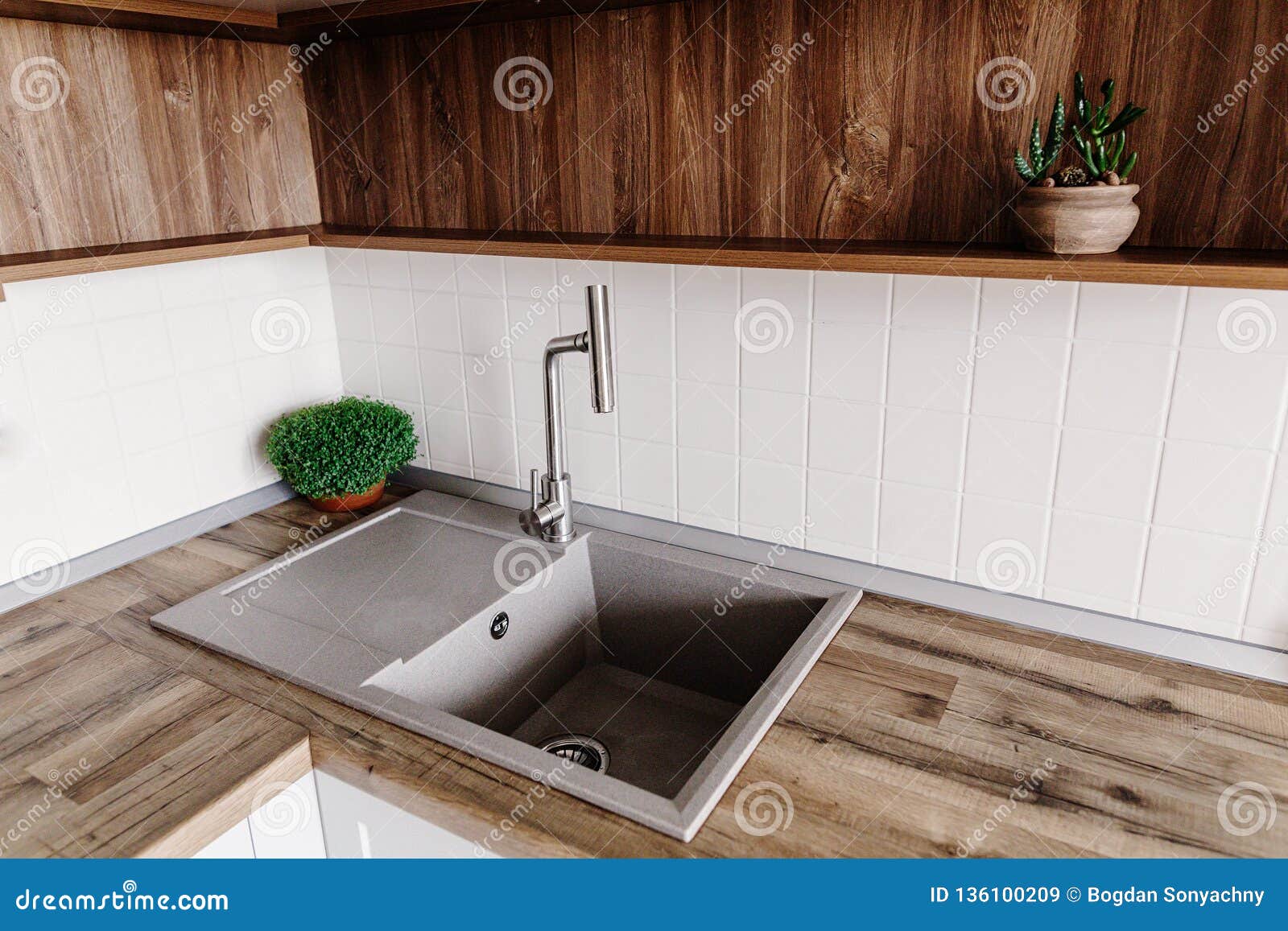与金属龙头的时髦的灰色水槽在有木桌面和植物的现代厨房在灰色颜色的时髦的厨房家具库存图片 图片包括有新建 国内
