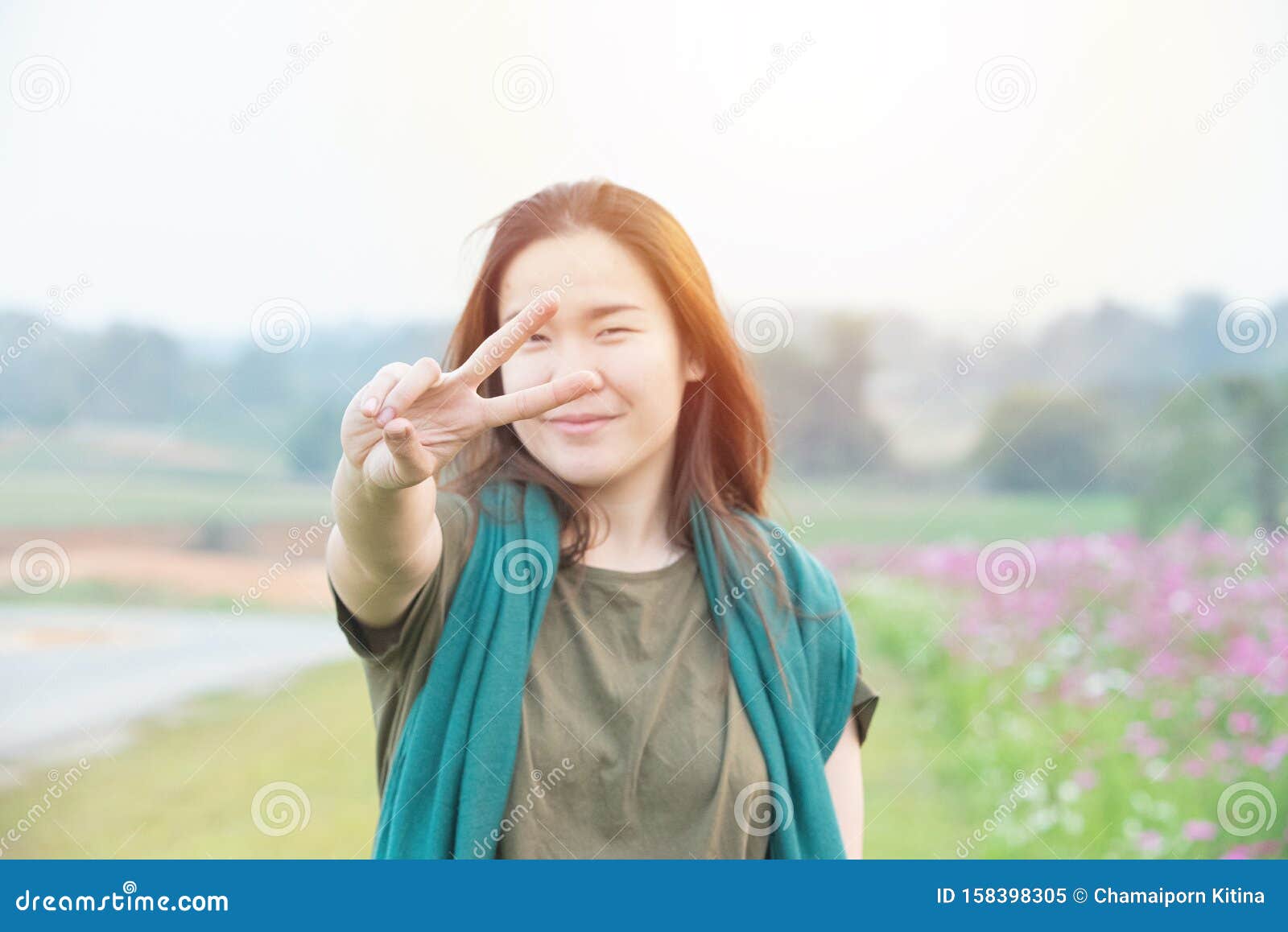 亚洲年轻女性微笑着看镜头 用宇宙田背景的手指展示和平标志的画像库存图片 图片包括有亚洲年轻女性微笑着看镜头 用宇宙田背景的手指展示和平标志的画像