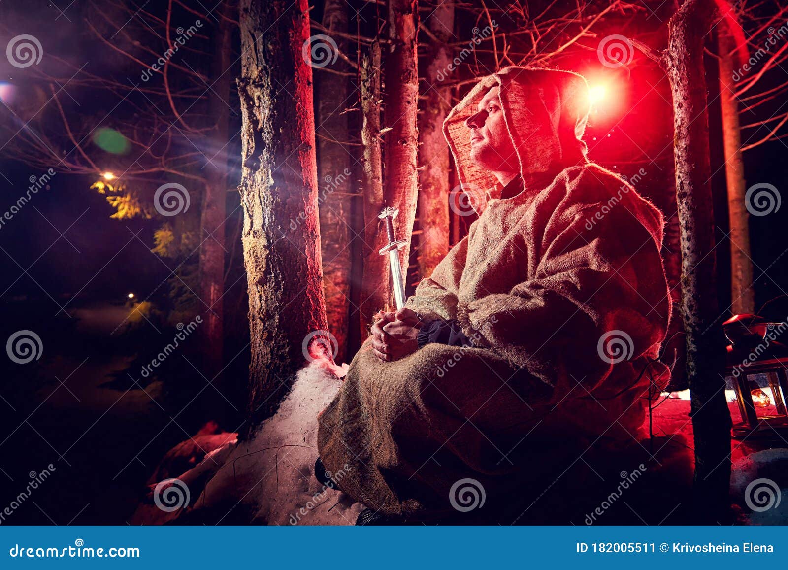 中世纪僧人帆布僧袍在黑森林中用雪和红光祈祷冬夜 幻想或童话故事库存图片 图片包括有大刀 全能