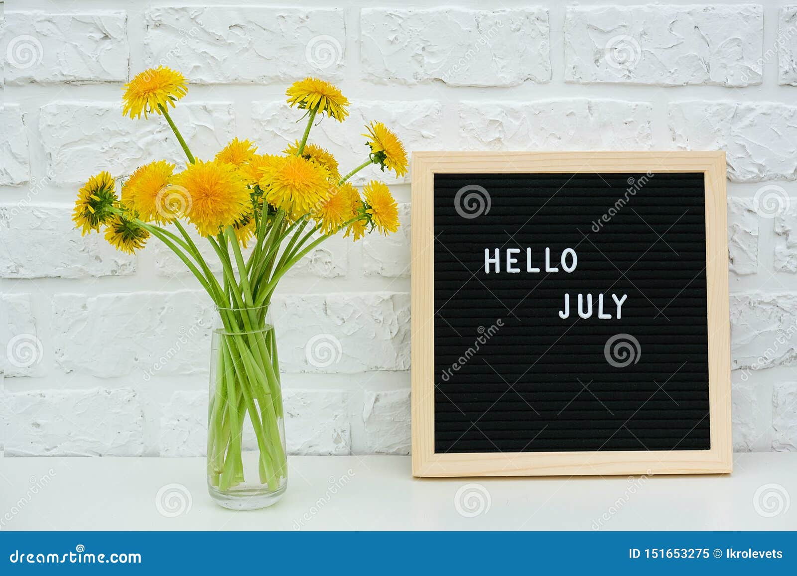 发短信给你好在哥特式黑体字黄色蒲公英花板和花束的7月在花瓶的在背景白色砖墙上 库存图片 图片包括有