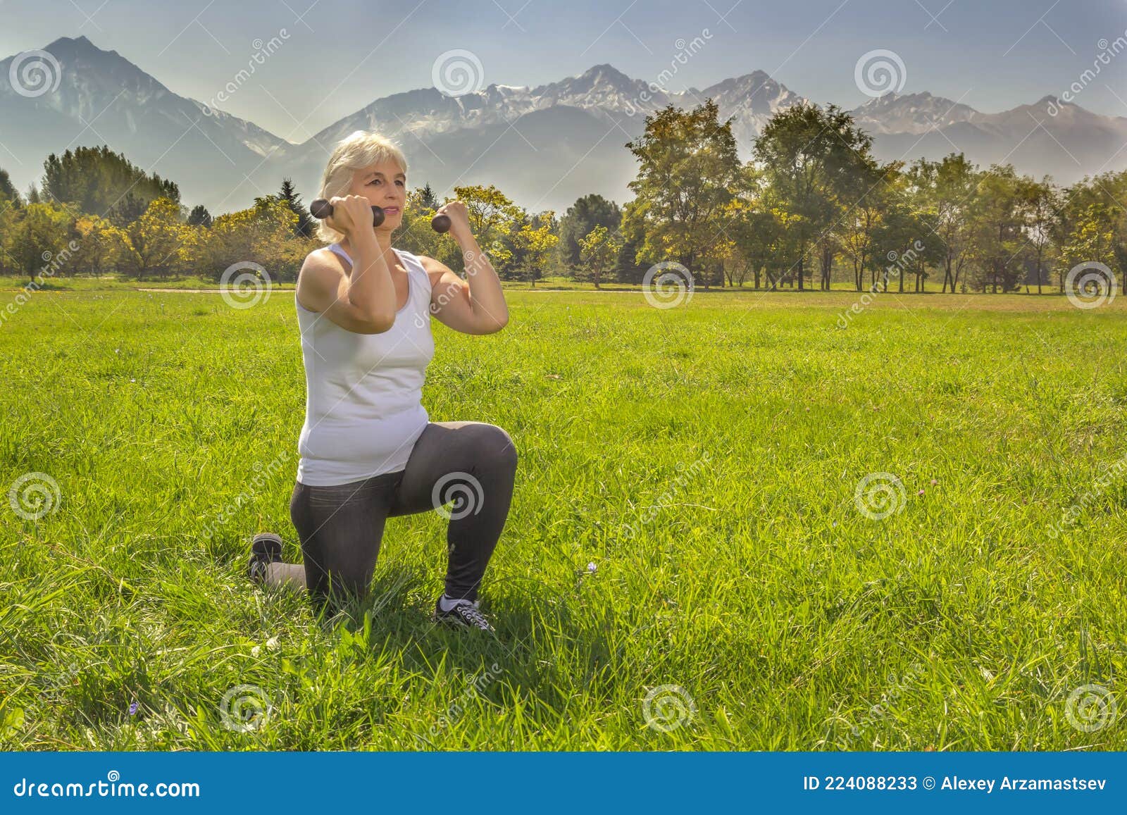 在山背景下在公园里健身时，年长的女性用哑铃蹲着库存图片. 图片包括有更老, 靠山, 女性, 业余爱好- 224088233