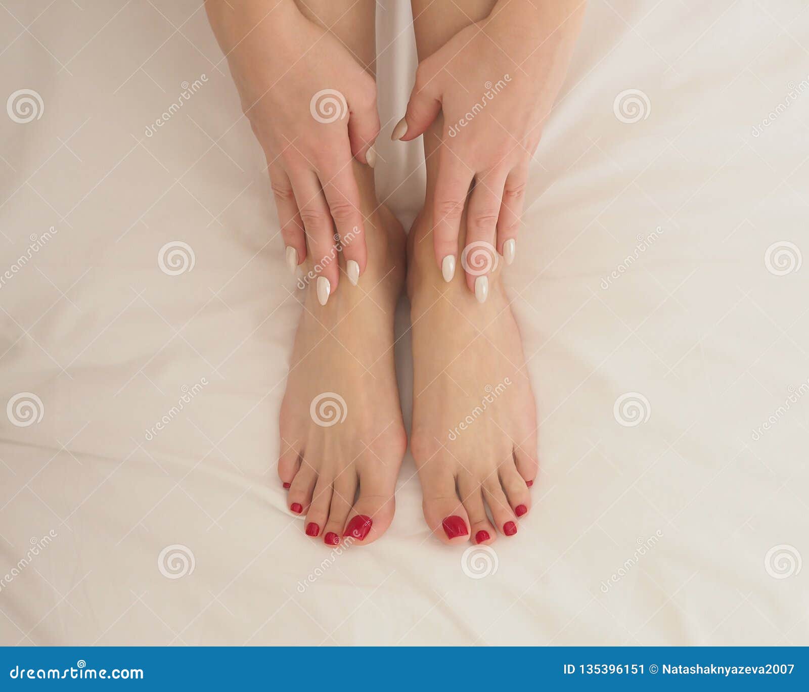 女性赤脚和手在白色卧具 关闭 正面图库存图片 图片包括有
