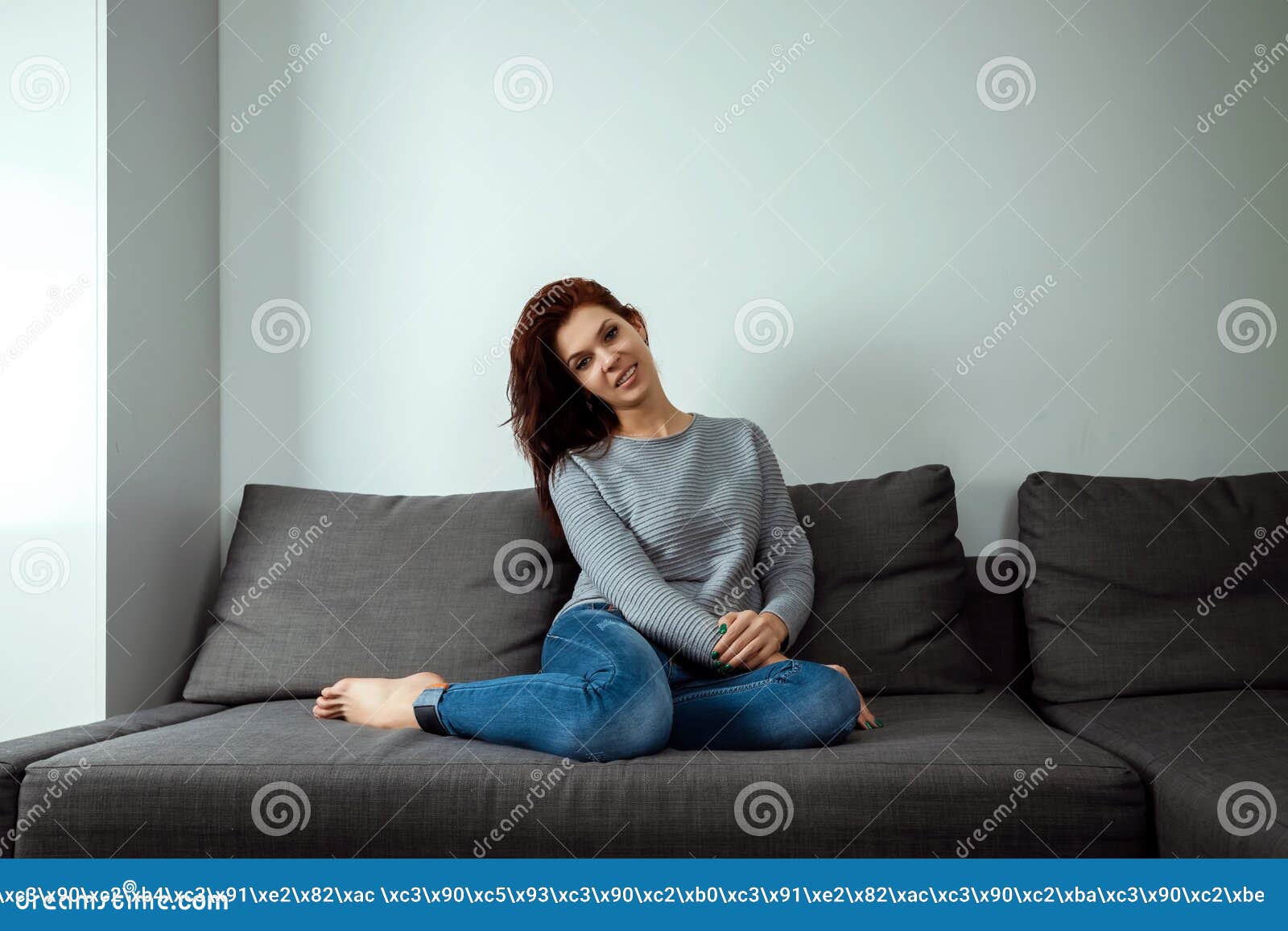 年轻作的妇女在家坐沙发查寻体贴的年轻女人坐在客厅和微笑的妇女库存图片 图片包括有