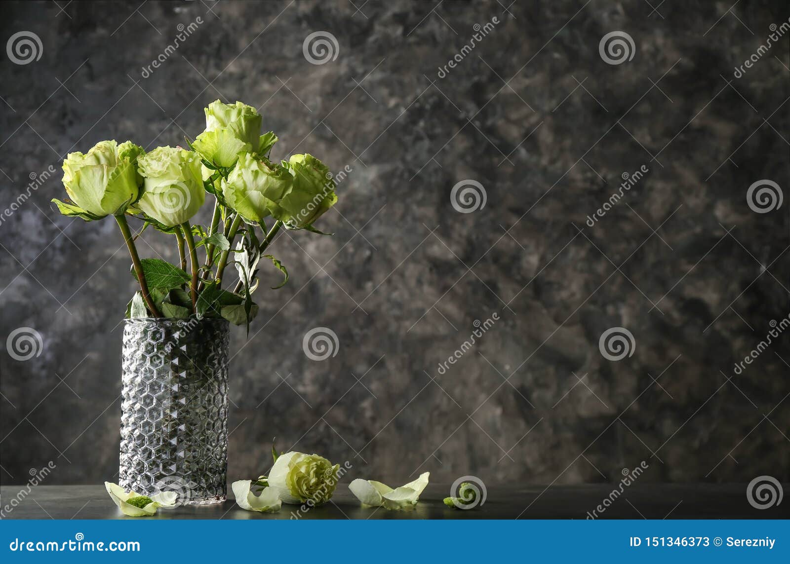 有绿蔷薇美丽的花束的花瓶在桌上的反对难看的东西背景库存图片 图片包括有