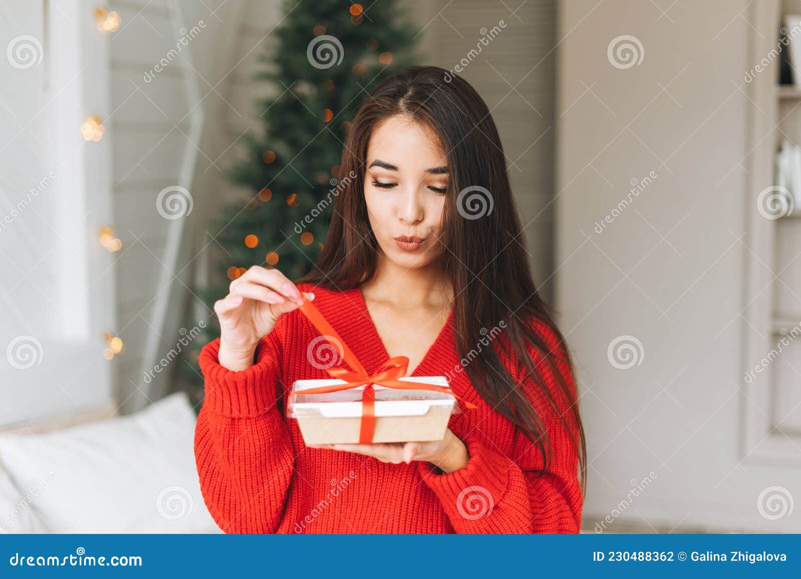 深长头发的亚洲年轻美女，舒适的红色针织毛衣和带红色丝带礼盒的圣诞帽  image