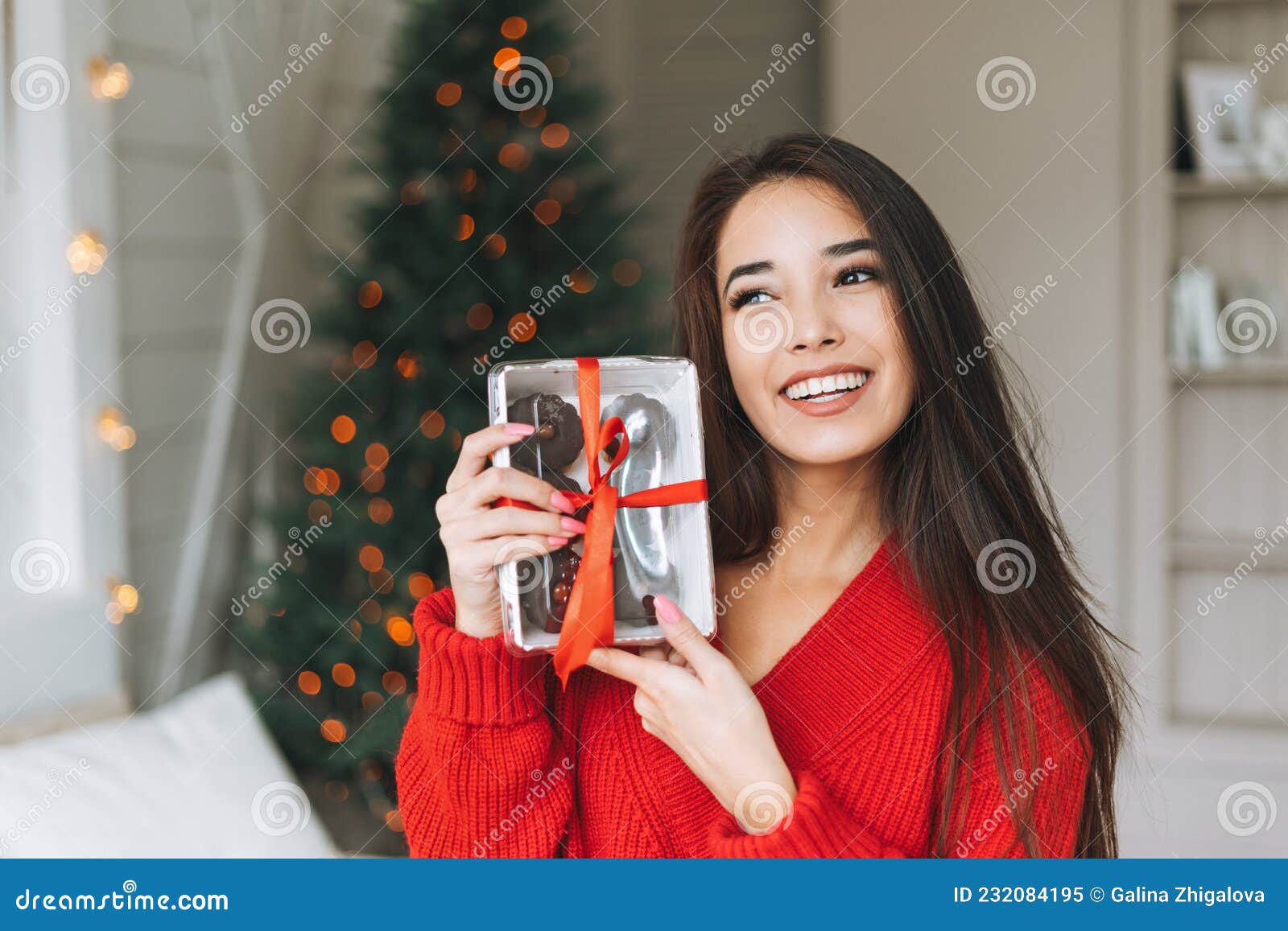 深长头发的亚洲年轻美女，舒适的红色针织毛衣和带红色丝带礼盒的圣诞帽  image