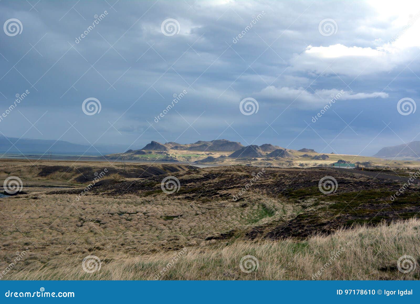 熔岩荒野在冰岛在西部海湾区域在遥远的山和风雨如磐的天空背景库存照片 图片包括有