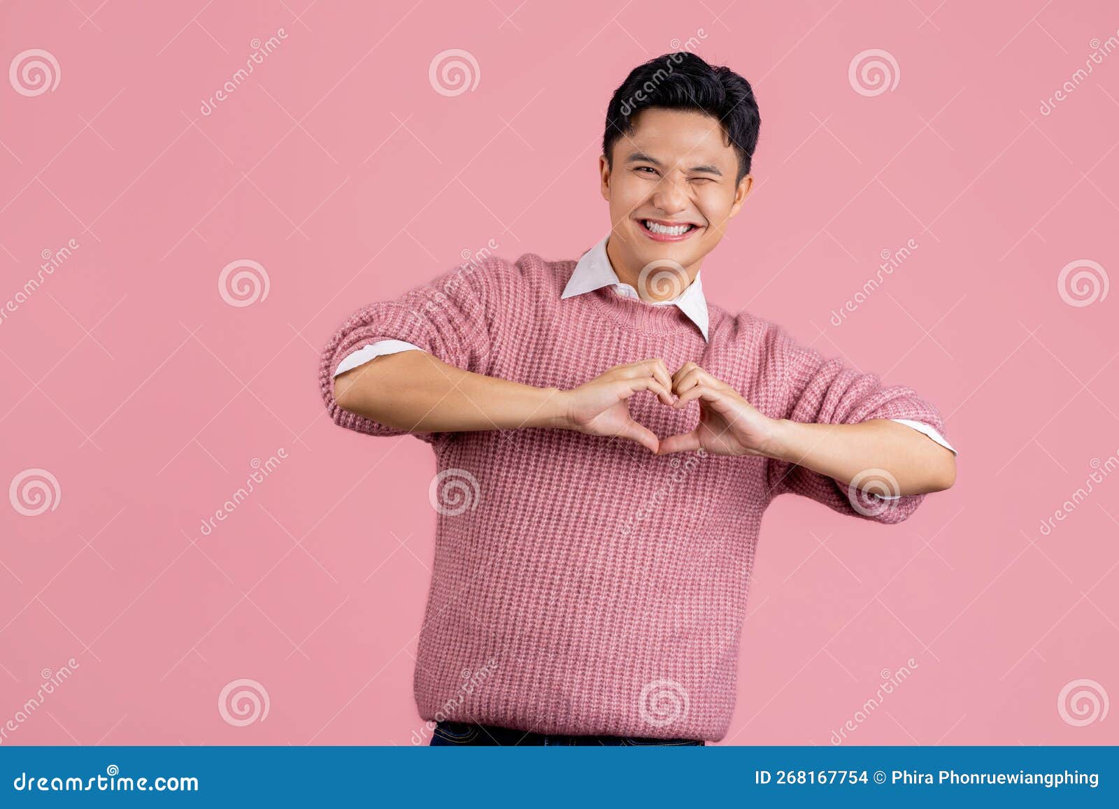 身穿休闲粉色毛衣的亚洲男青年热爱地用双手做心形符号形状. 浪漫概念  image