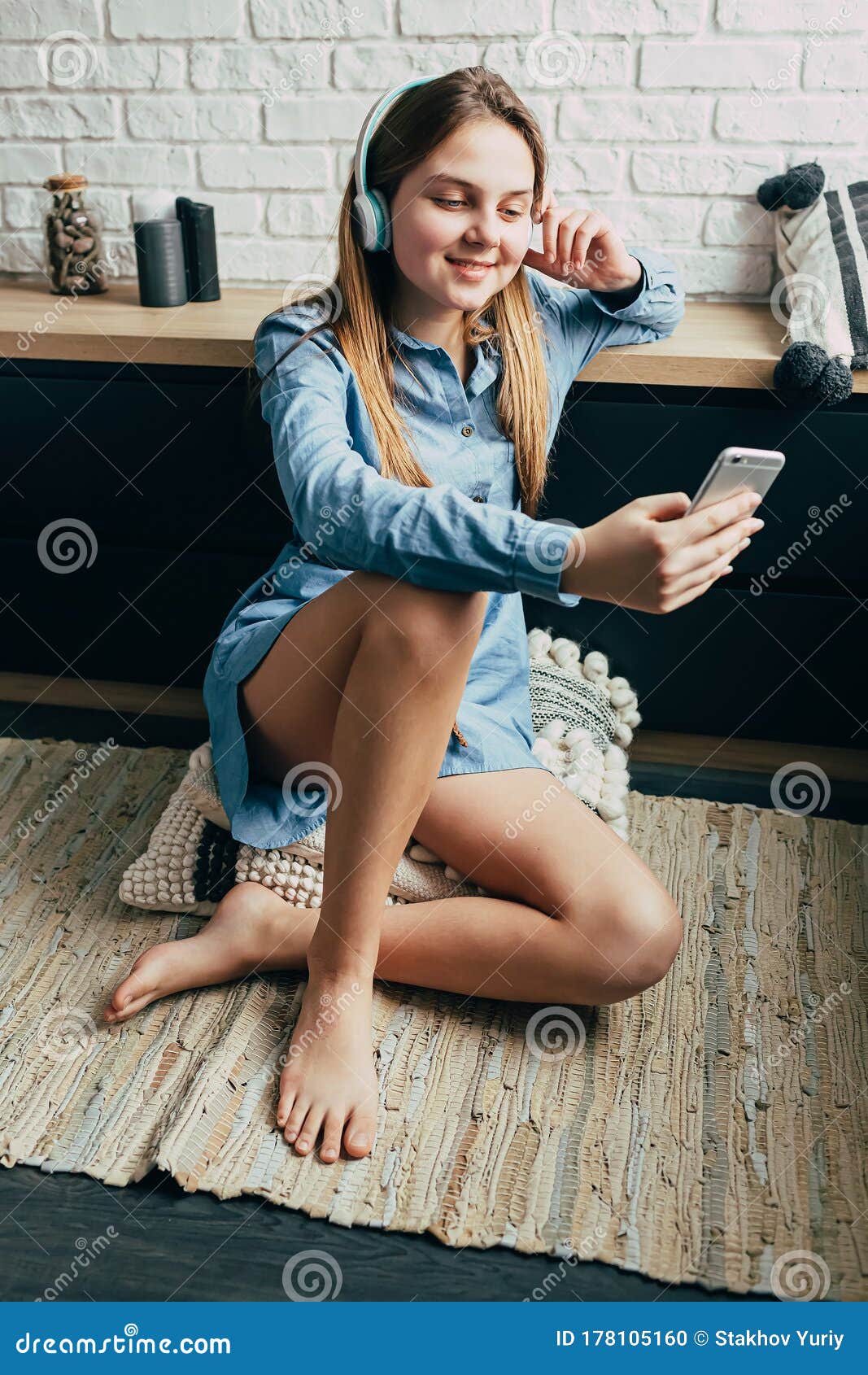 身穿蓝色衬衫的白人漂亮少年坐在公寓的地板上 公寓里有漂亮的阁楼内饰 看着手机库存照片 图片包括有白种人 通信 身穿蓝色衬衫的白人漂亮少年坐在公寓的地板上 公寓里有漂亮的阁楼内饰 看着手机库存照片 图片包括有白种人 通信