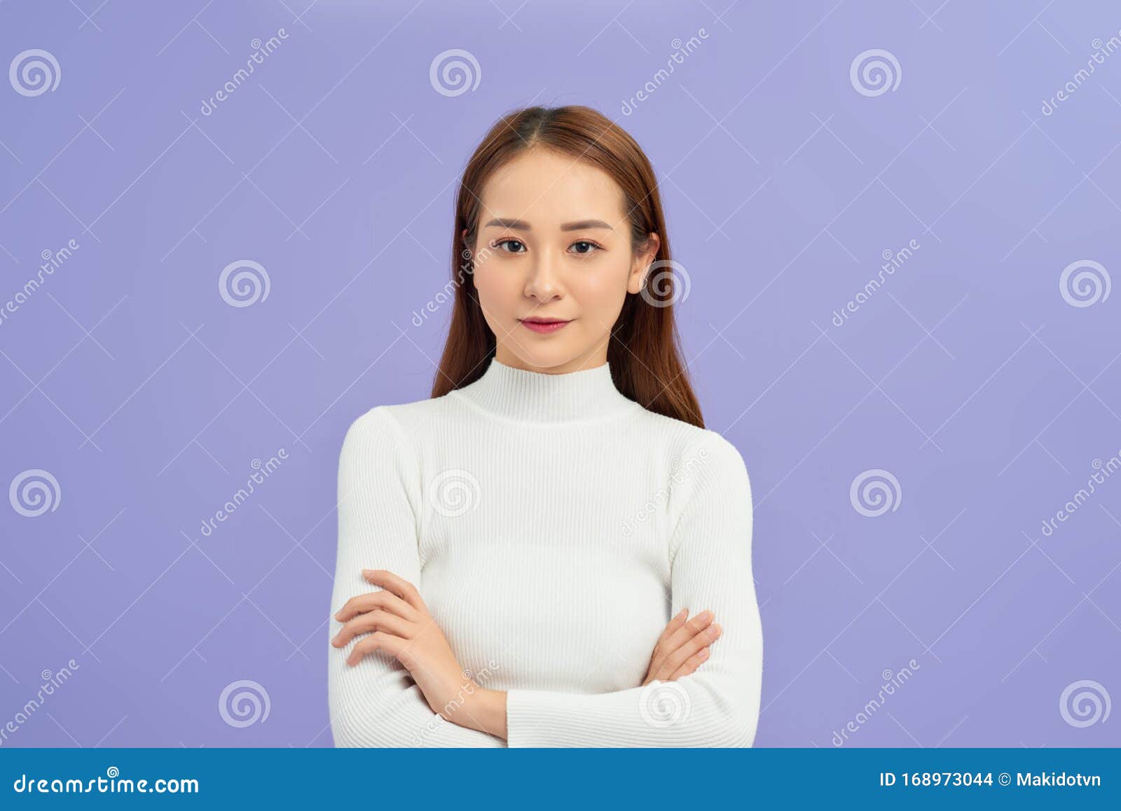 身穿高领毛衣的亚洲女青年站在白色背景中，面带交叉双臂的笑脸库存照片  image