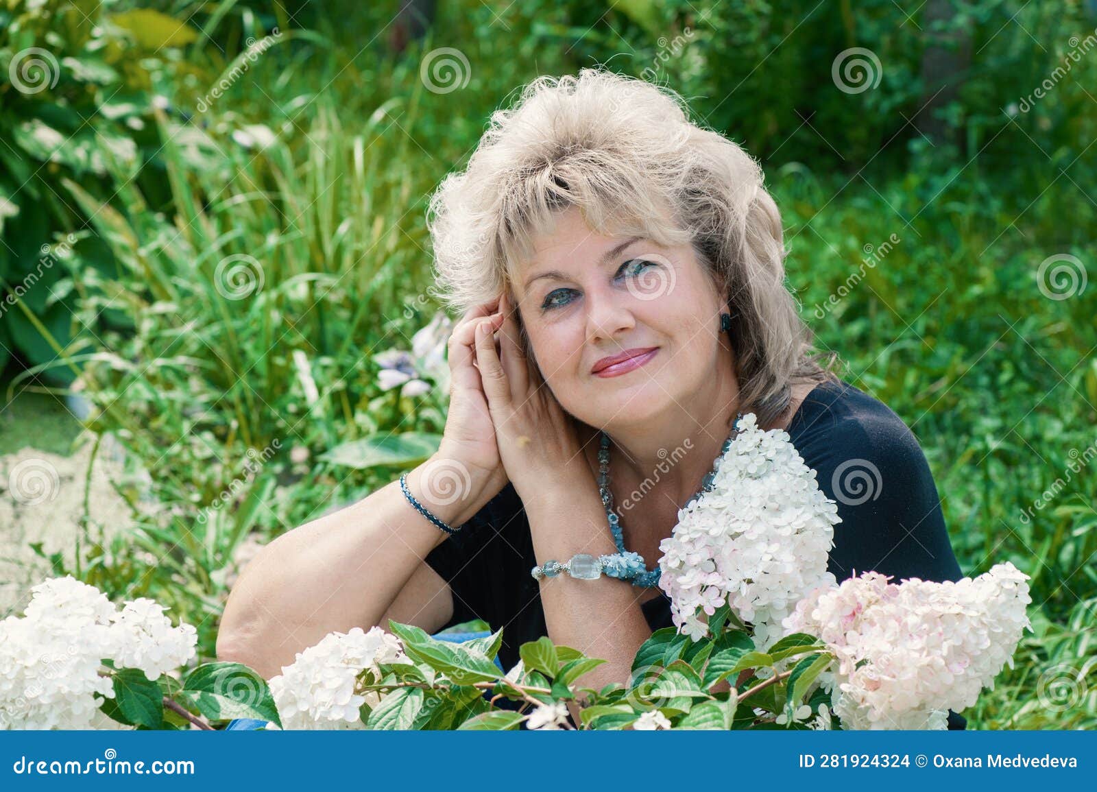 60 Year Old Woman In The Garden A Mature Woman Enjoys The Flowers Of A Hydrangea Grown With Her