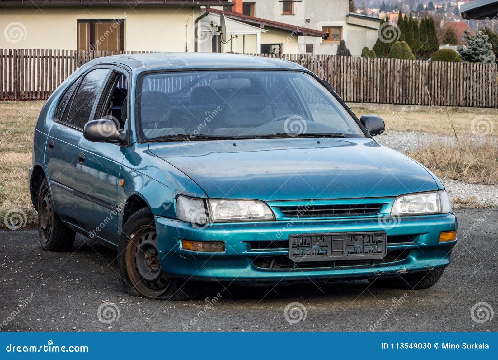 abandoned azure blue japanese hatchback car with a flat tire