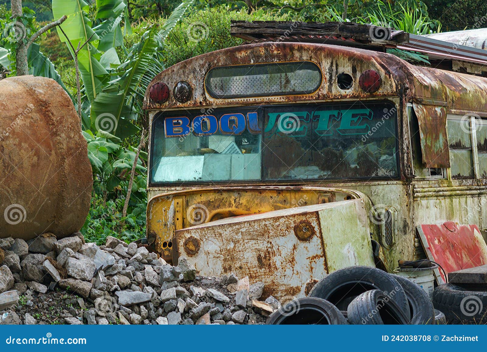 an abandoned schol bus rusts in a junkyard near boqueue panama