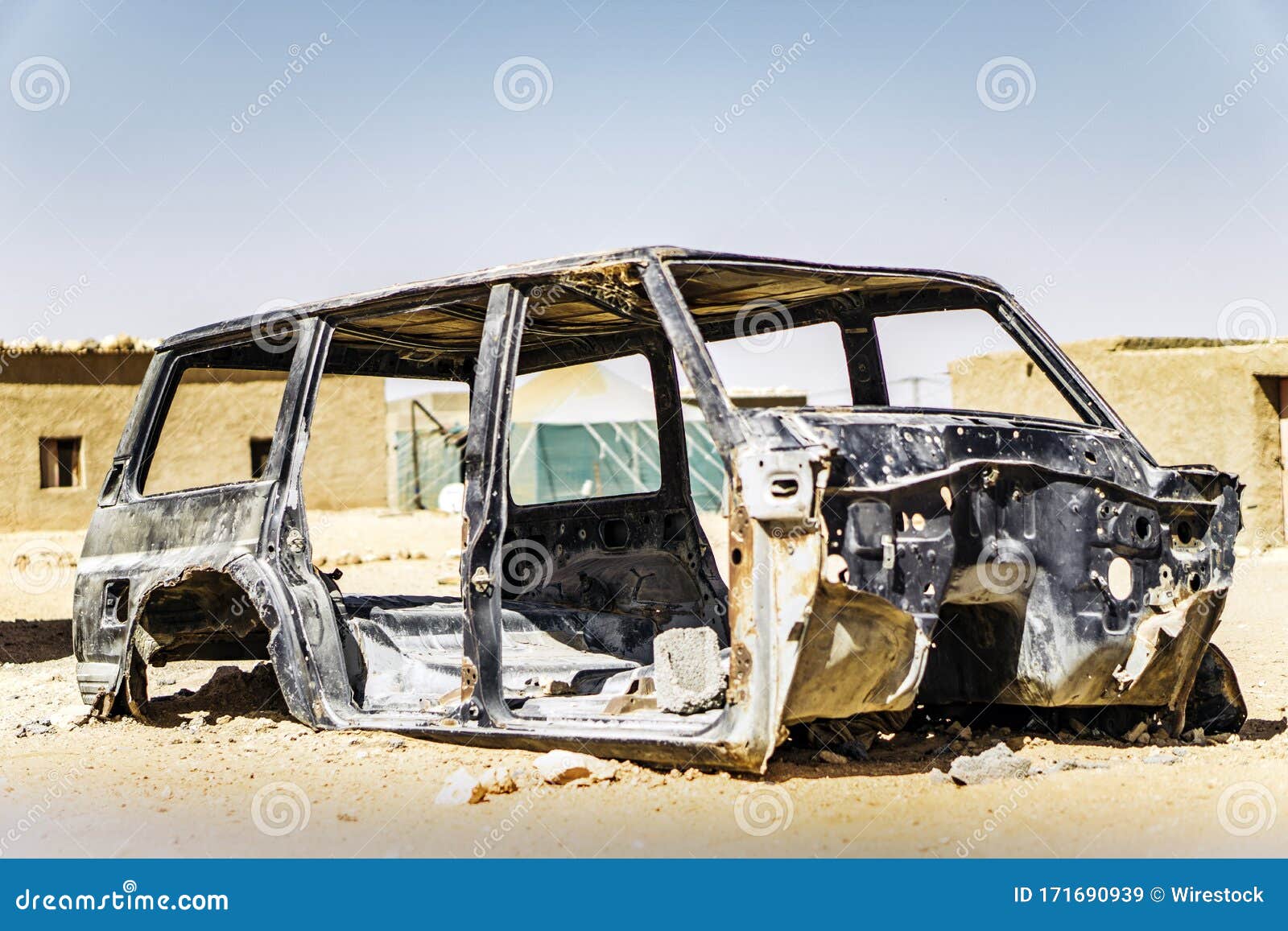 Abandoned Scrapped Car in a Refugee Camp on a Sunny Day Stock Image