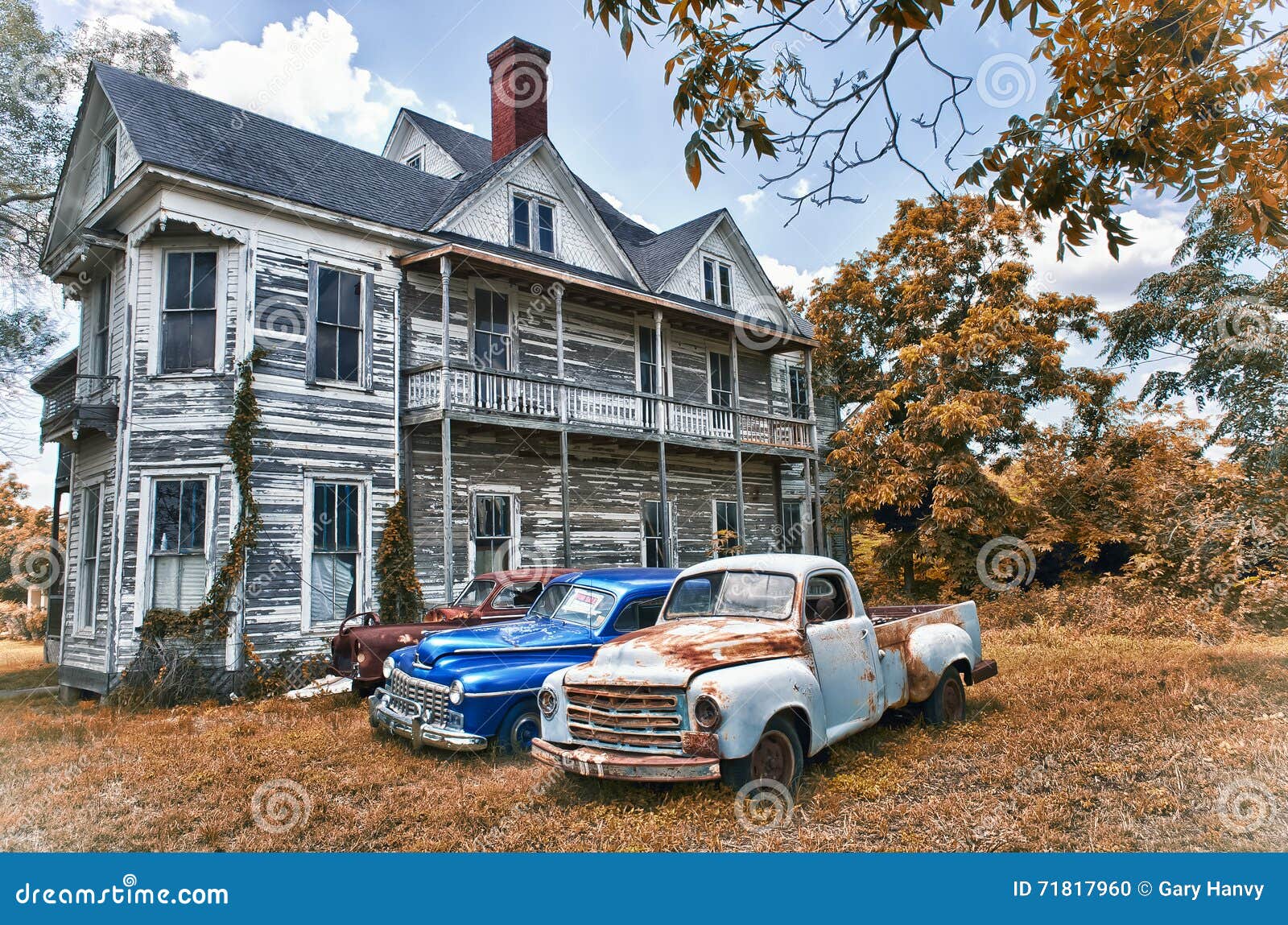 abandoned two story farmhouse with three vintage automobiles