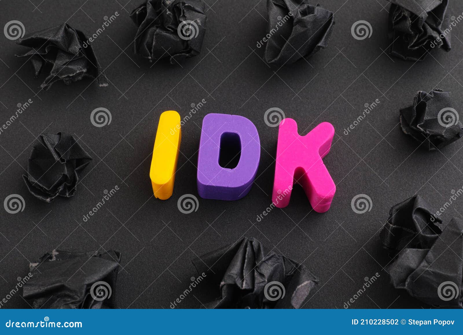 the abbreviation idk i don`t know made out of polymer clay letters with some black crumpled paper balls around it