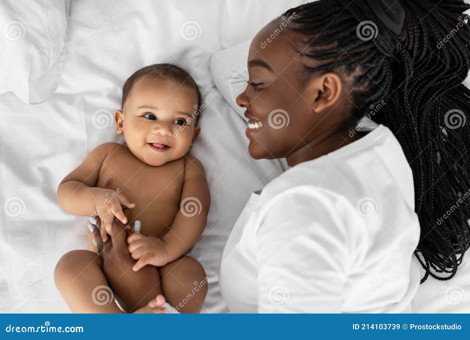 african american mom lying in bed with her cute infant