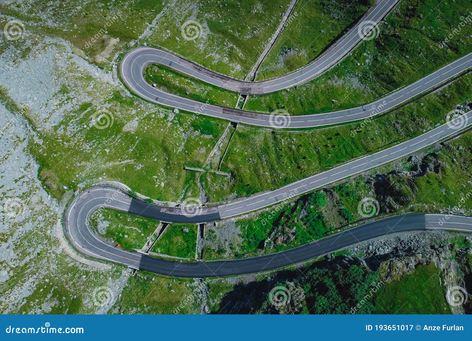 above view of epic winding road on transfagarasan pass in romania in summer time, with twisty road rising up. road crossing