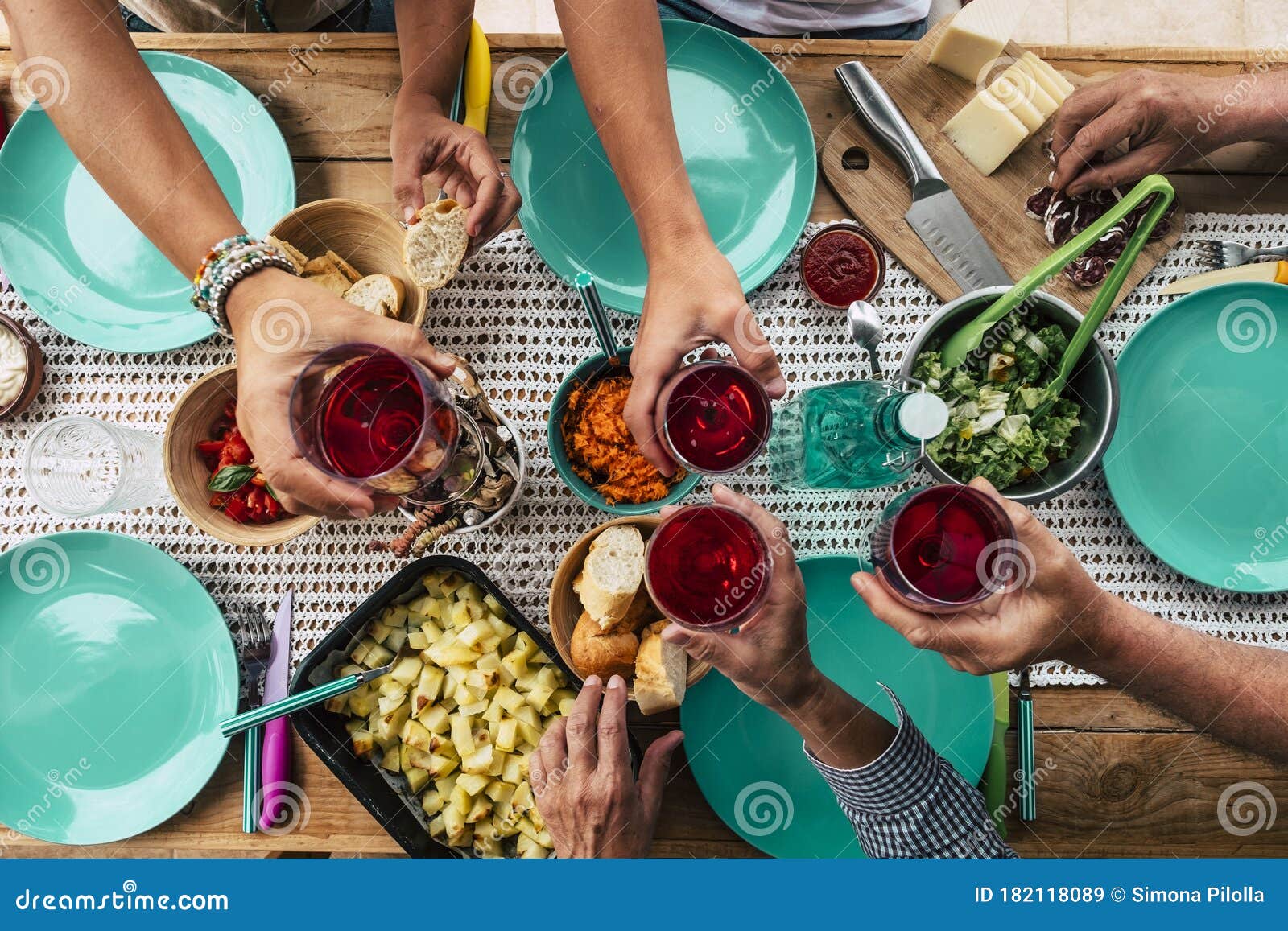 above view of group of friends people eat and drink together celebrating and having fun toasting with red wine - coloured table