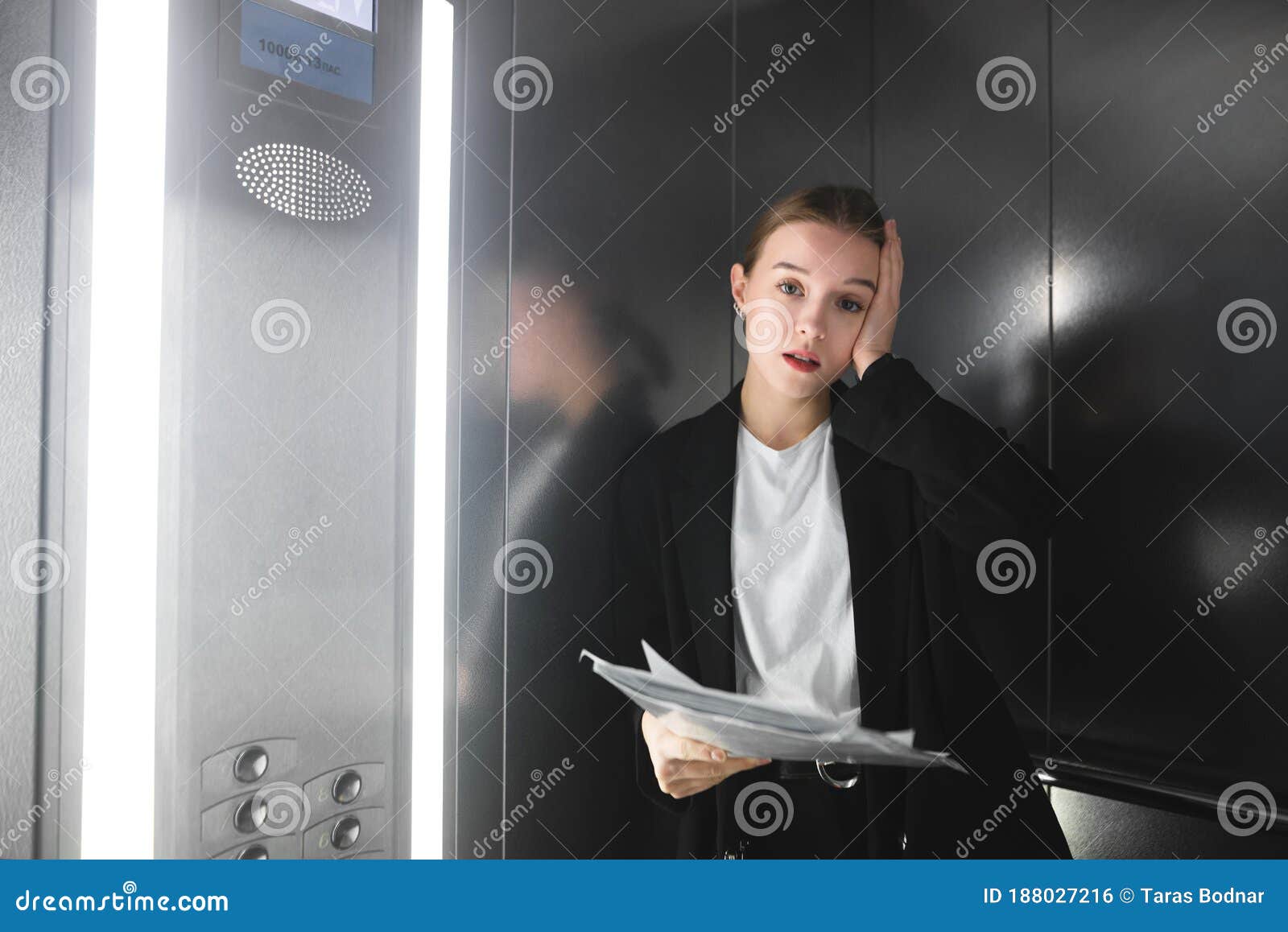 absolutely fed up businesswoman in elevator looking at camera holding the documents. frustrated female office worker holding the