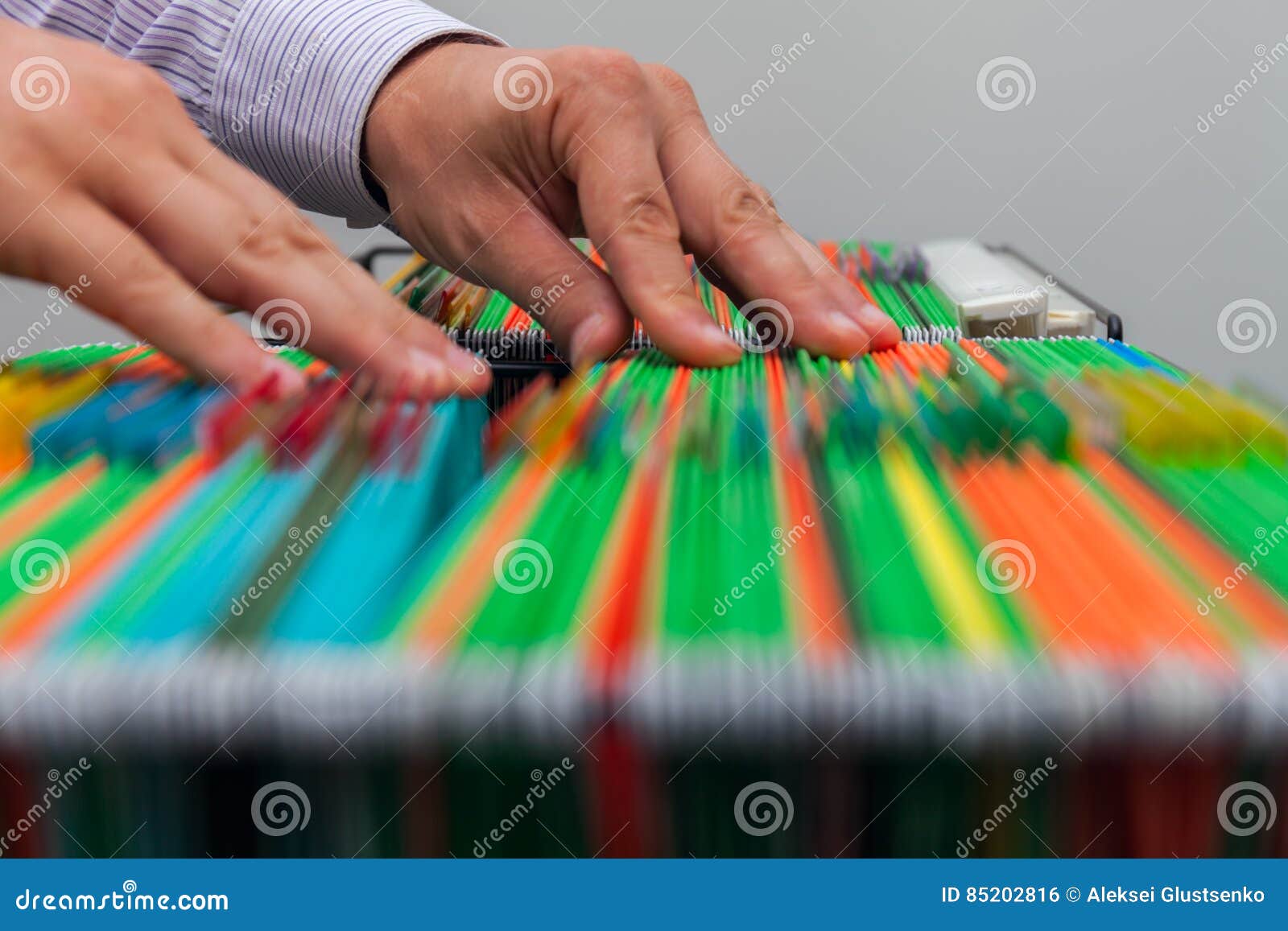 abstract background colorful hanging file folders in drawer. male hands looking document in a whole pile of full papers