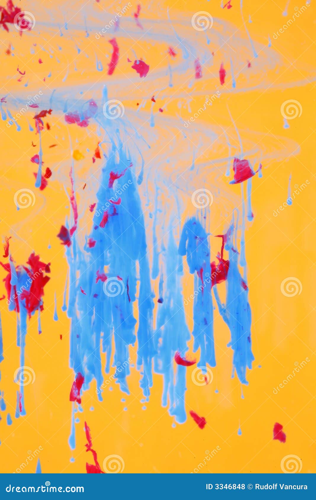 A view of abstract liquid art suitable for a background, with blue and red ink dissolving and sinking to the bottom of a glass container in a clear liquid against an yellow background.