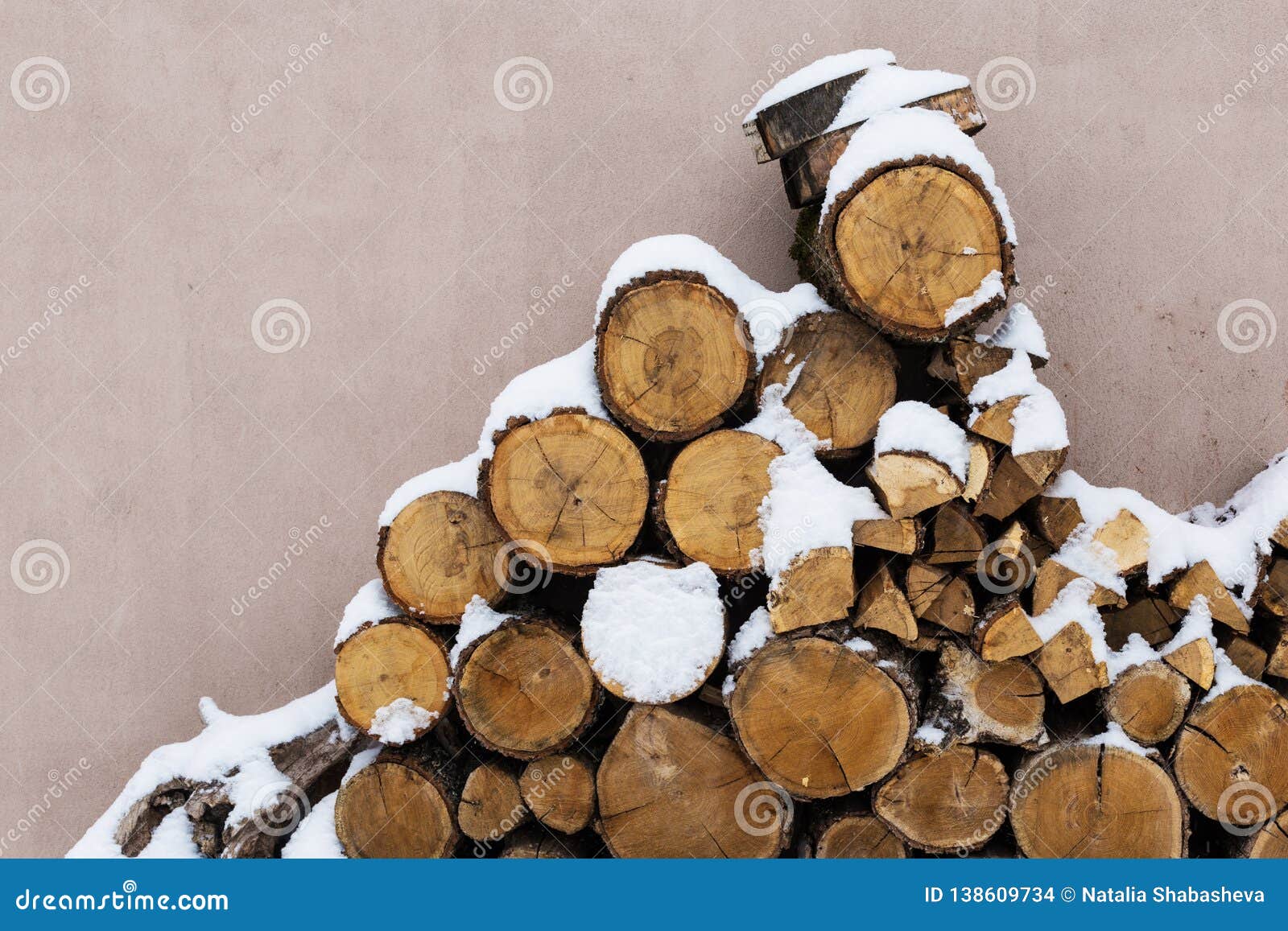 Acción tajada de la leña debajo de la nieve en la calle Leña para la chimenea y el Bbq. Leña apilada en invierno Pila de madera con la nieve apilada para la leña Pilas de leña nevada en el día de invierno frío