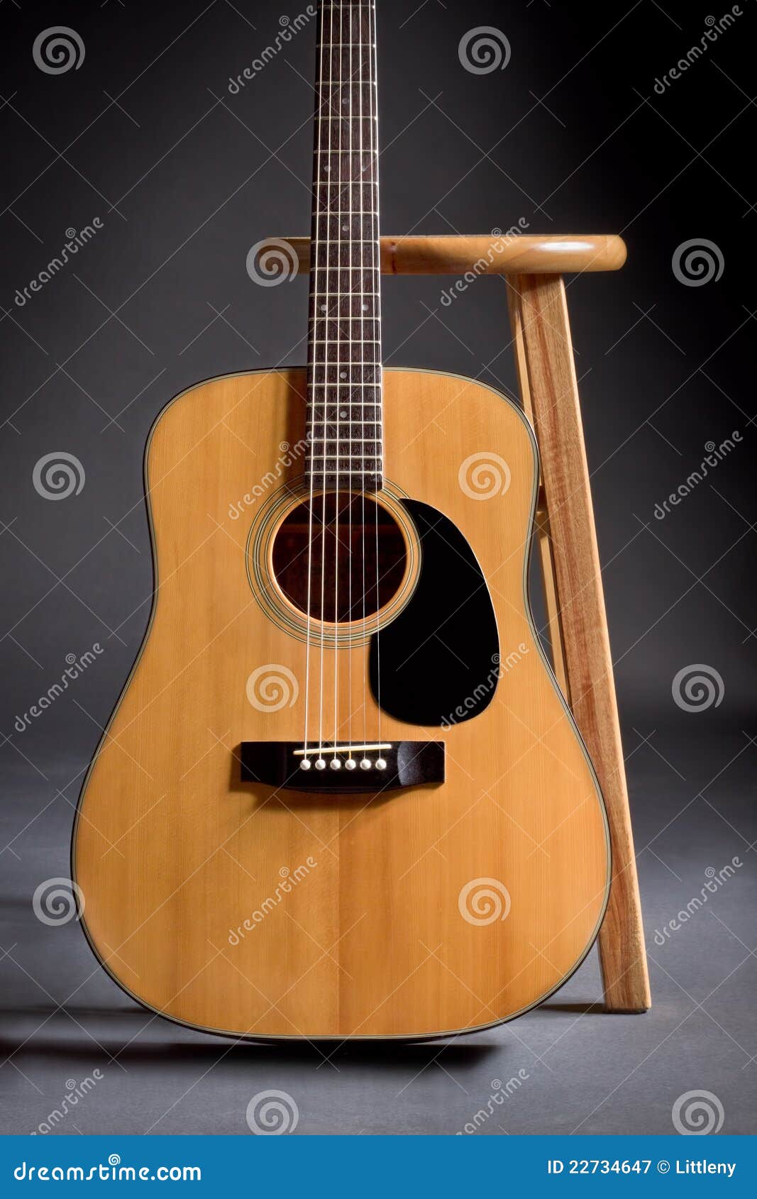 Acoustic guitar leaning against a wooden stool