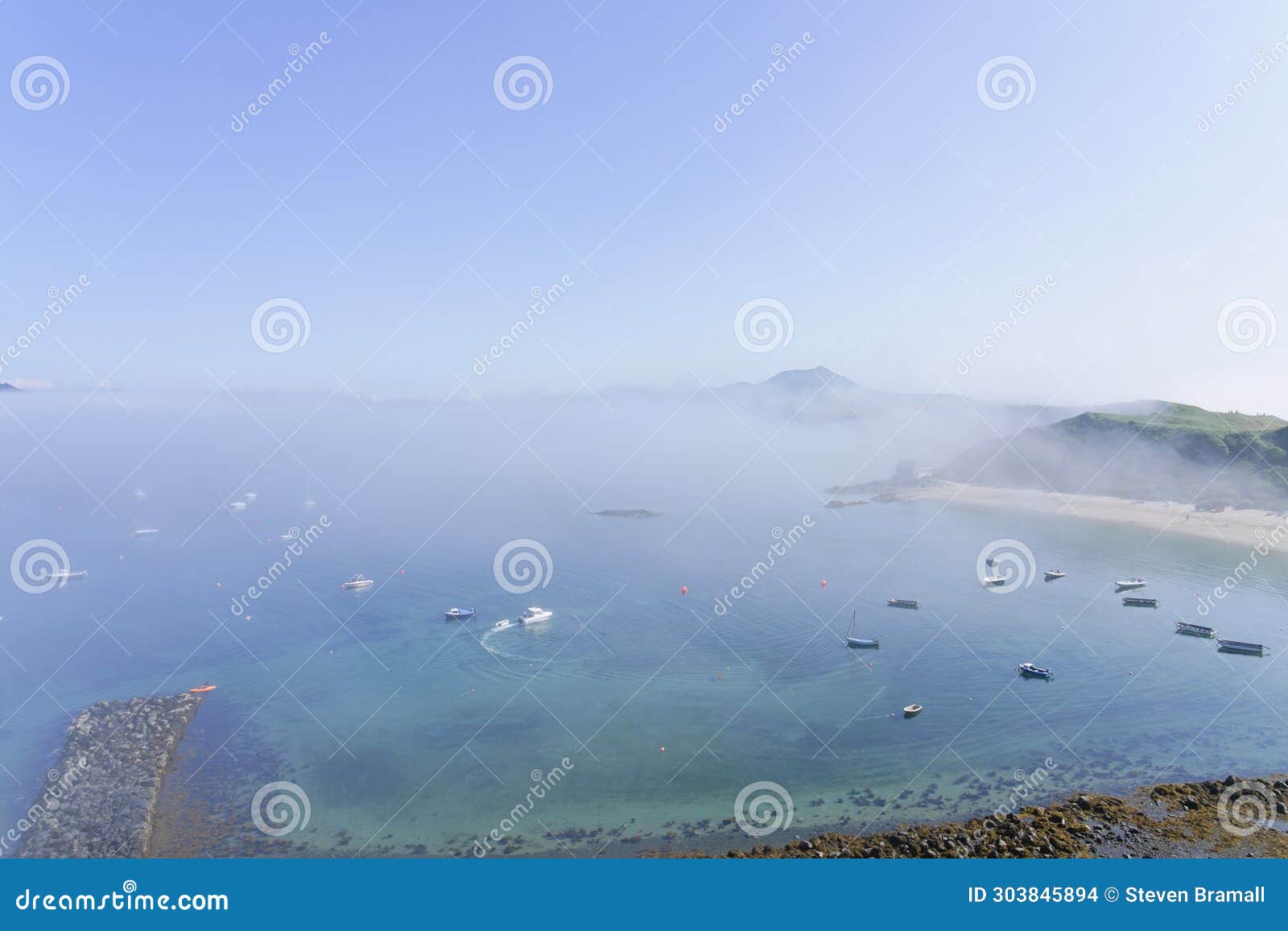 high above porthdinllaen harbour looking across to the distant mountain tops on a foggy day in june.