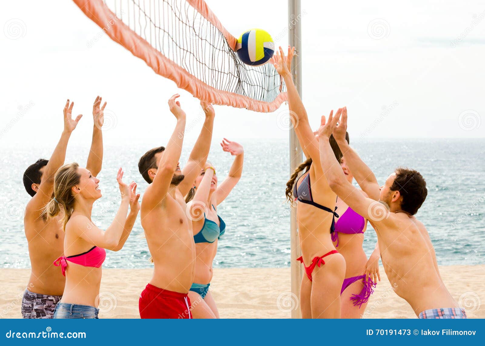 Actieve volwassenen die beachvolley spelen. Actieve gelukkige volwassenen die bal op een zandig de zomerstrand werpen dichtbij blauwe overzees