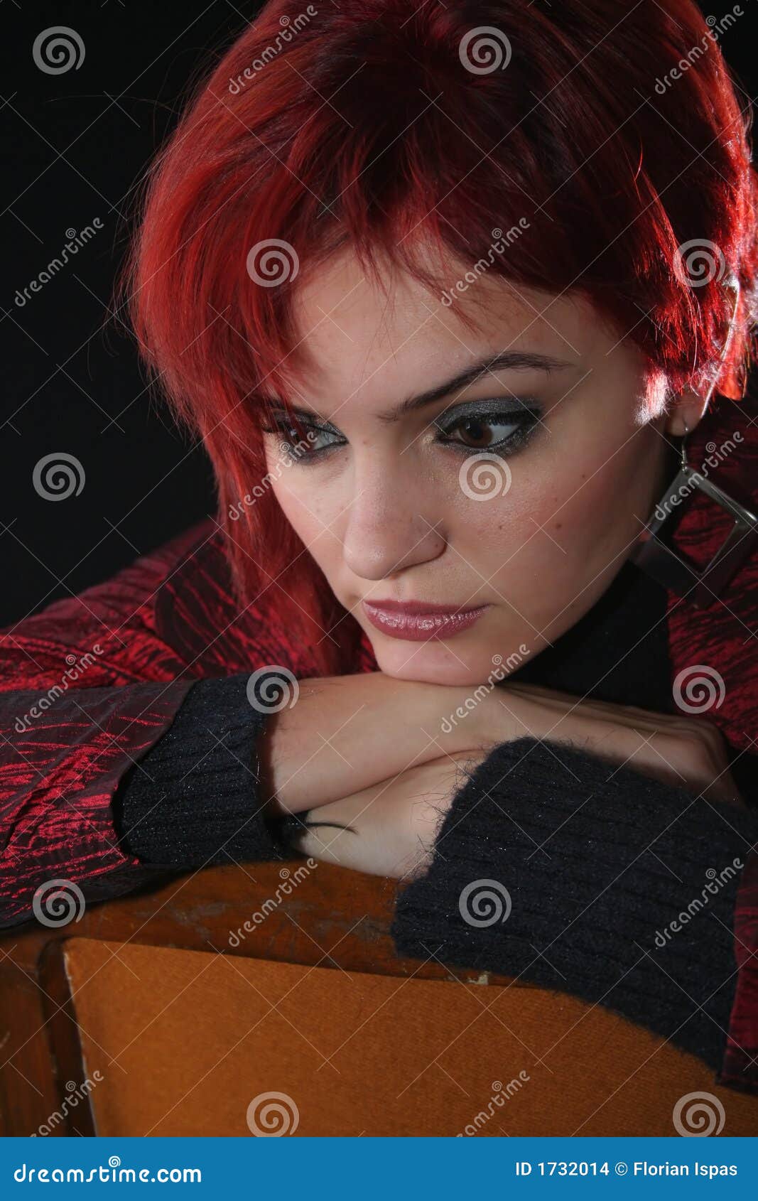 Actitud de una mujer joven. Mujer joven con el pelo rojo que piensa, fondo negro