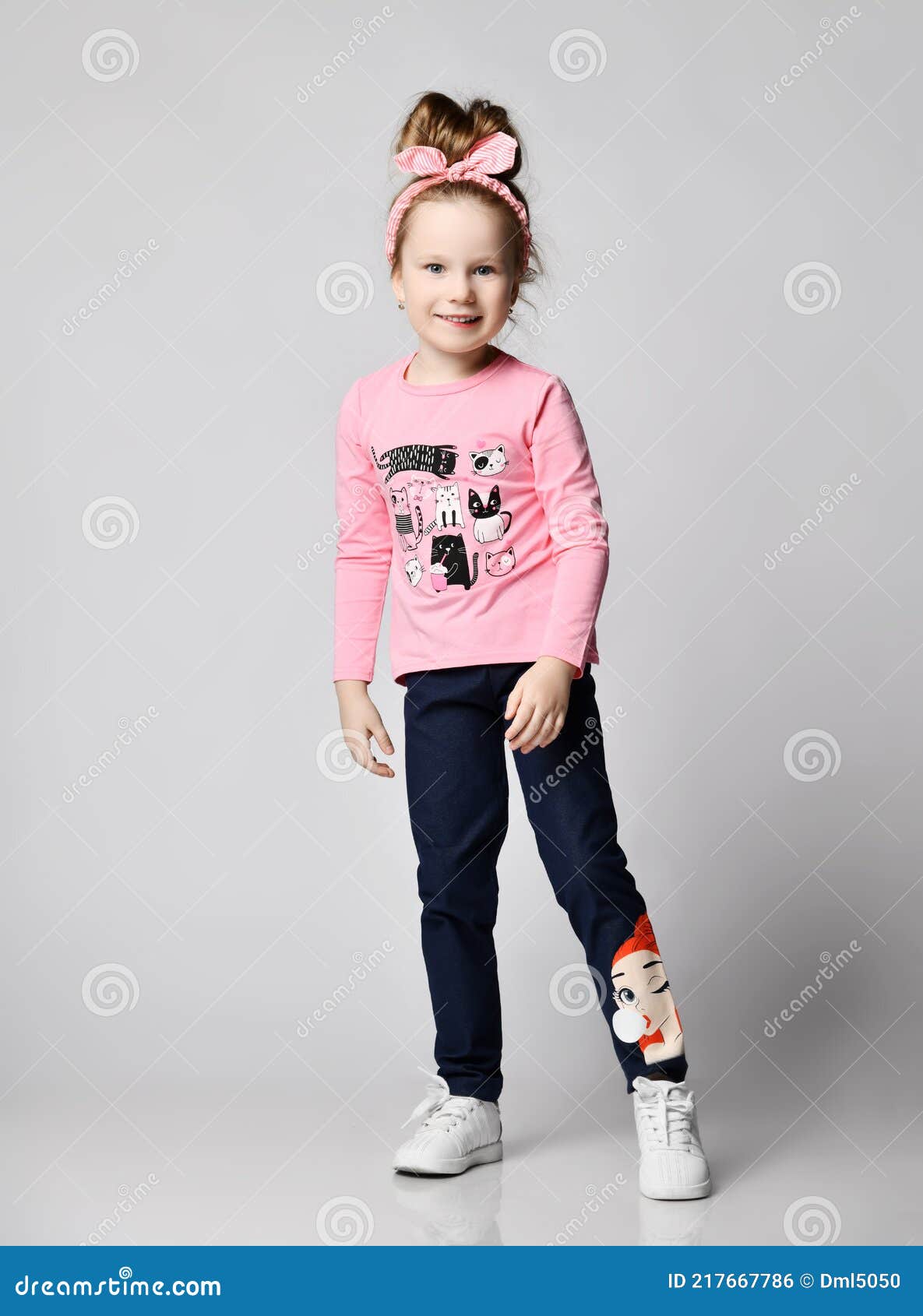 Activa Divertirse Niño Niña En Rosa Manga Larga Camiseta Y Zapatillas De Deporte Stands Que Muestran Impresión En Blue Jeans Foto de archivo sonrisa, divertido: 217667786