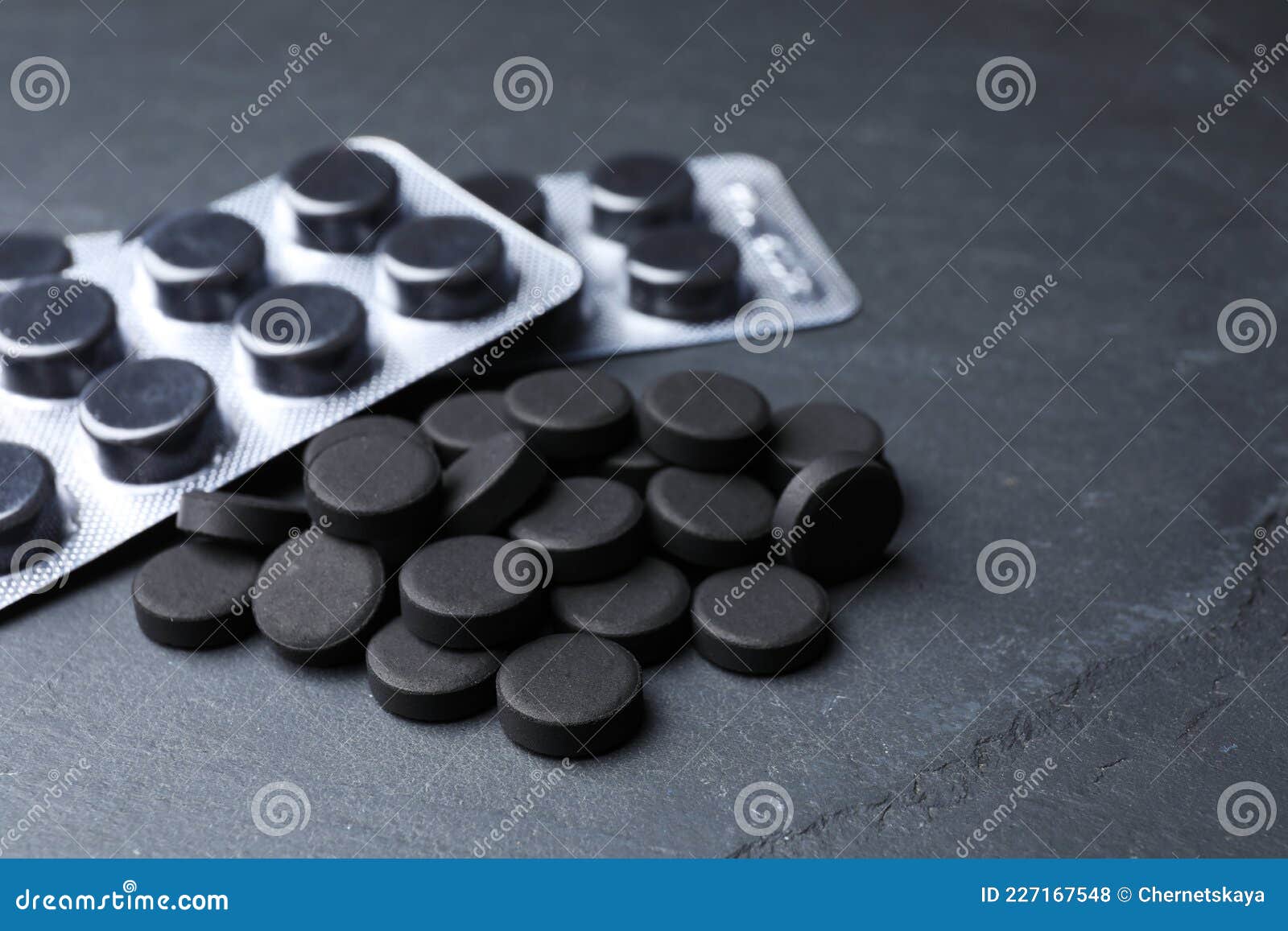 activated charcoal pills on black table, closeup. potent sorbent